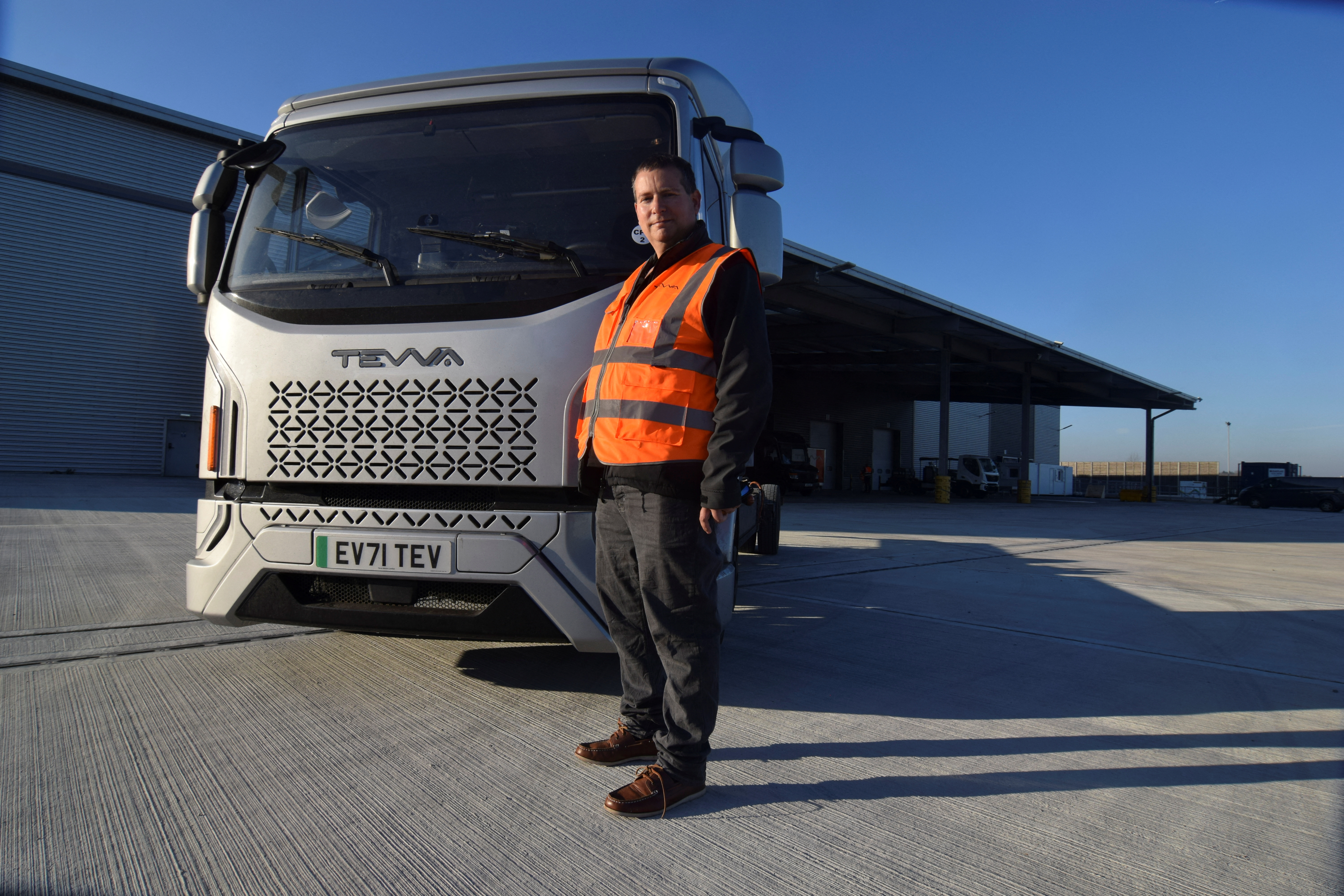 Asher Bennett, CEO of electric truck maker Tevva, poses for a photo in front of a pre-production prototype truck at the startup's UK plant, in Tilbury