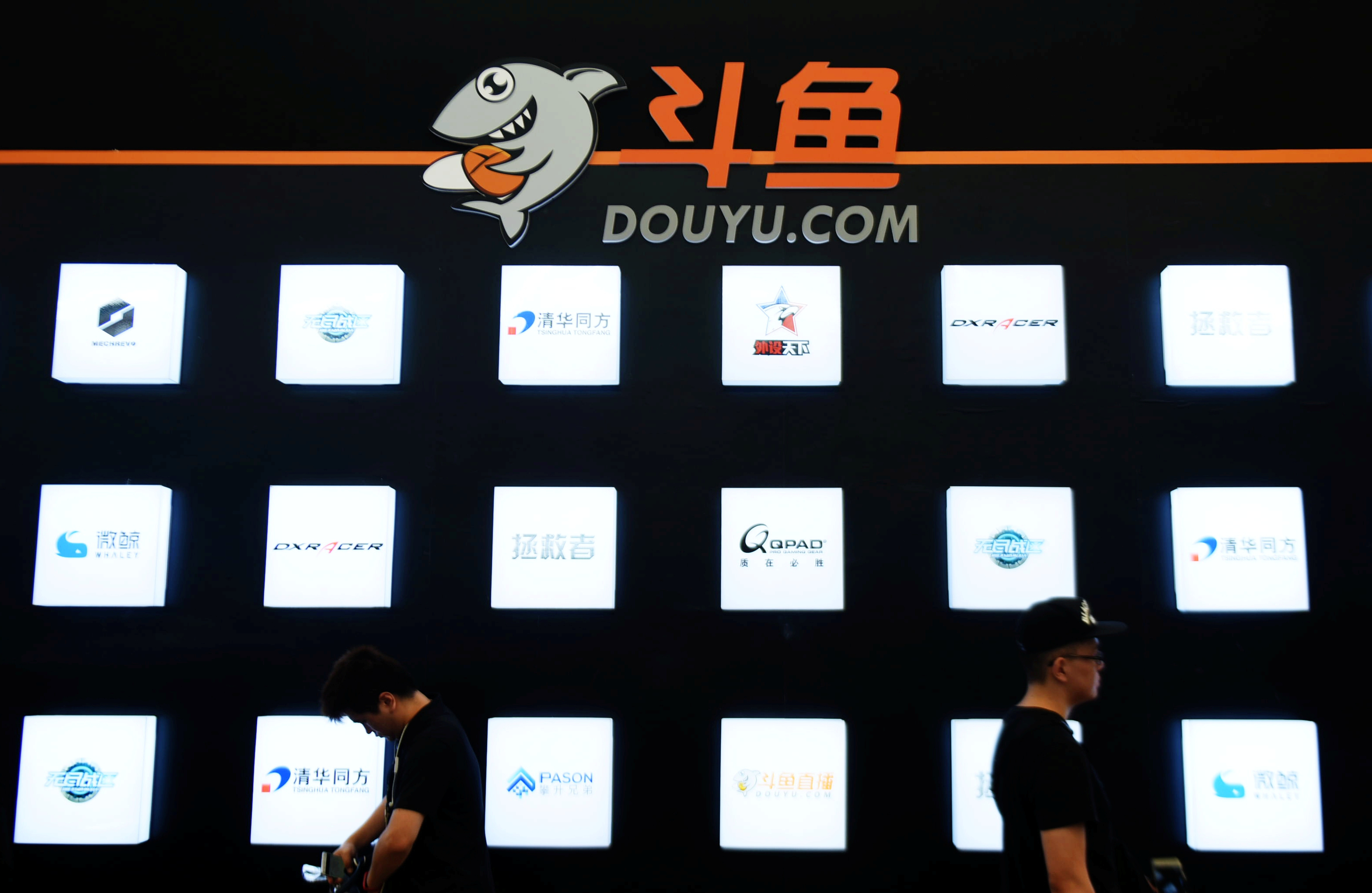 People walk past a booth of live-streaming platform Douyu at the ChinaJoy digital entertainment expo in Shanghai