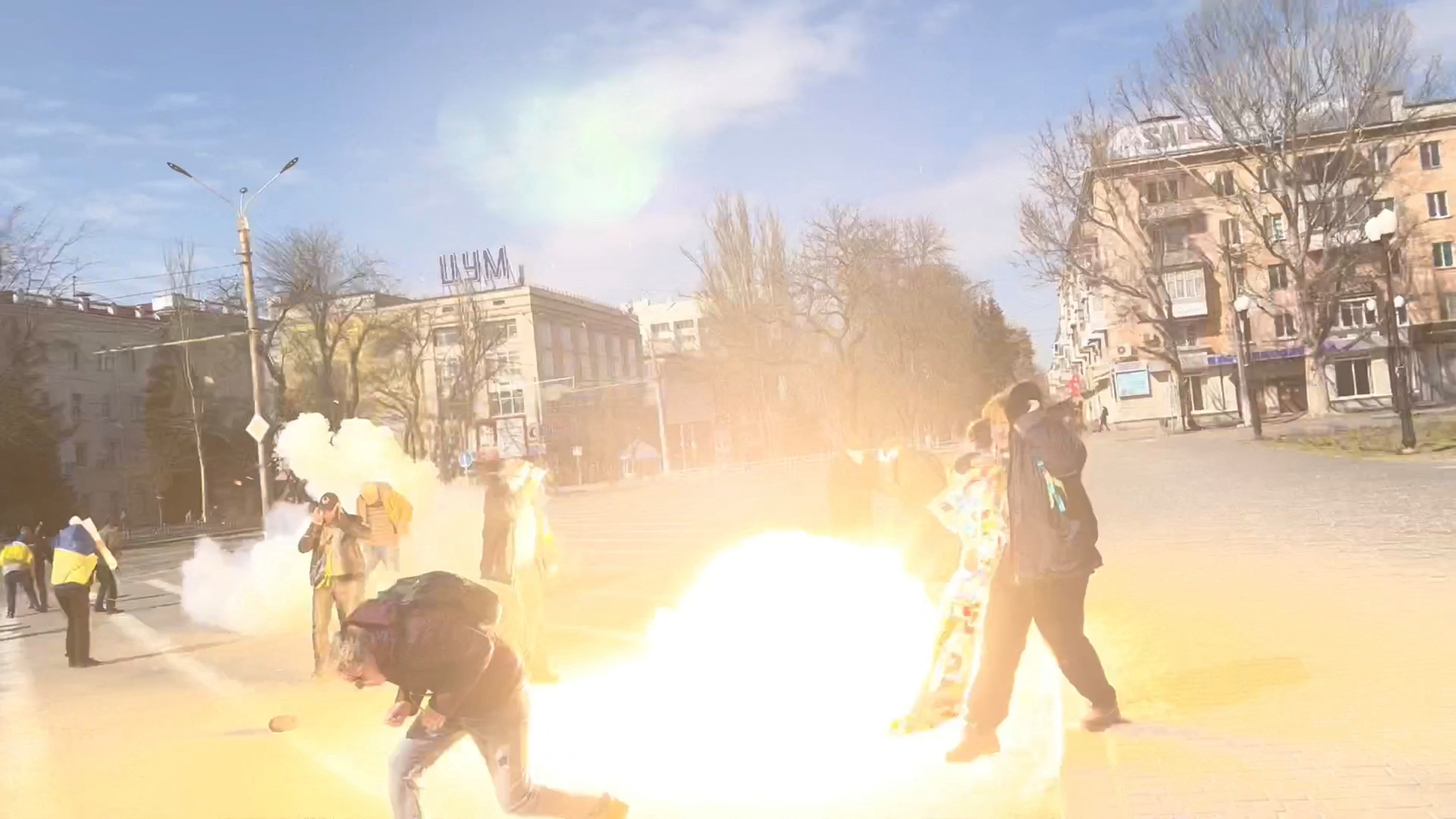 Demonstrators react to stun grenades thrown by Russian troops in Kherson