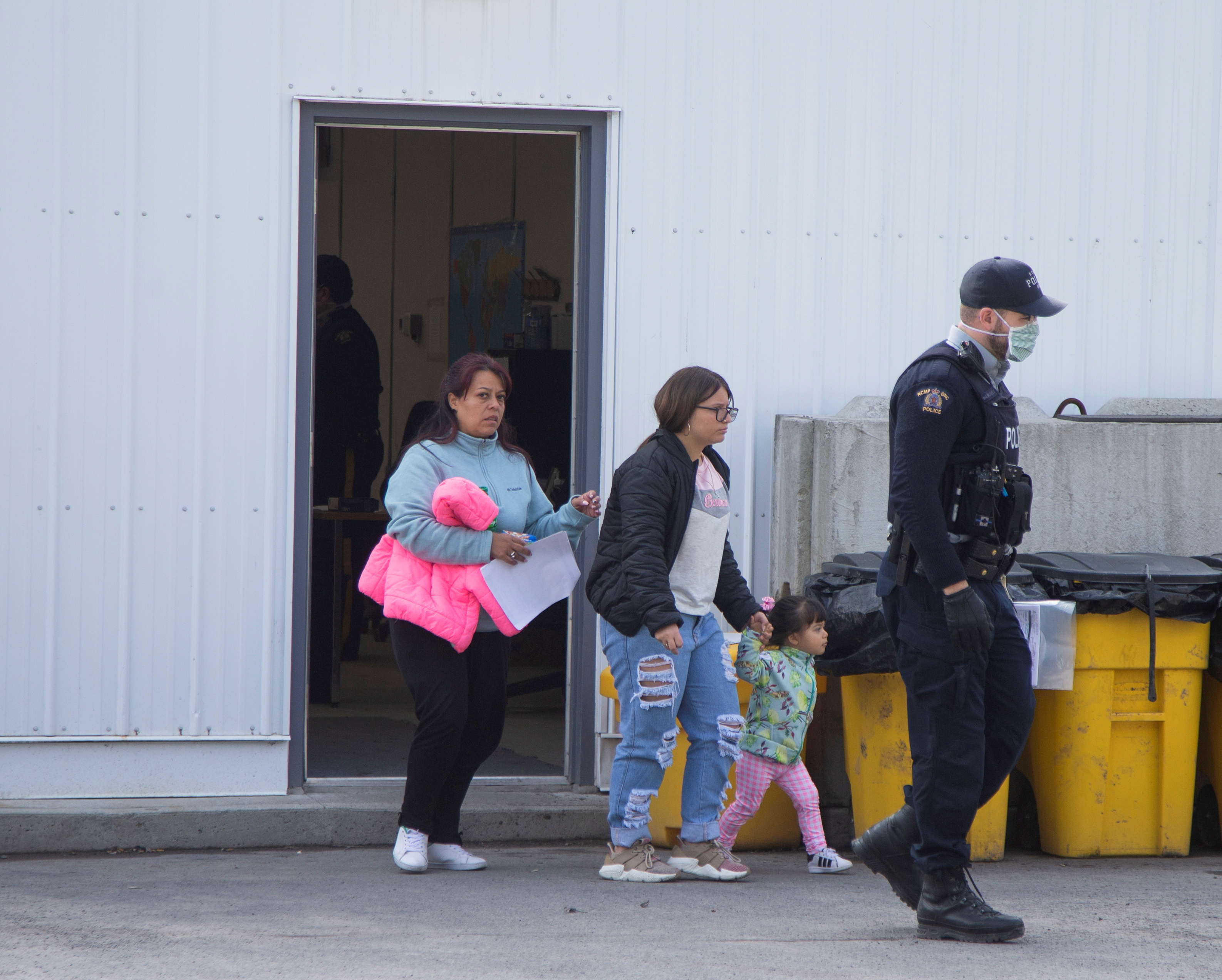 Asylum seekers follow a Royal Canadian Mounted Police (RCMP) officer after being processed for crossing the border from New York into Canada at, Roxham Road, in Hemmingford, Quebec