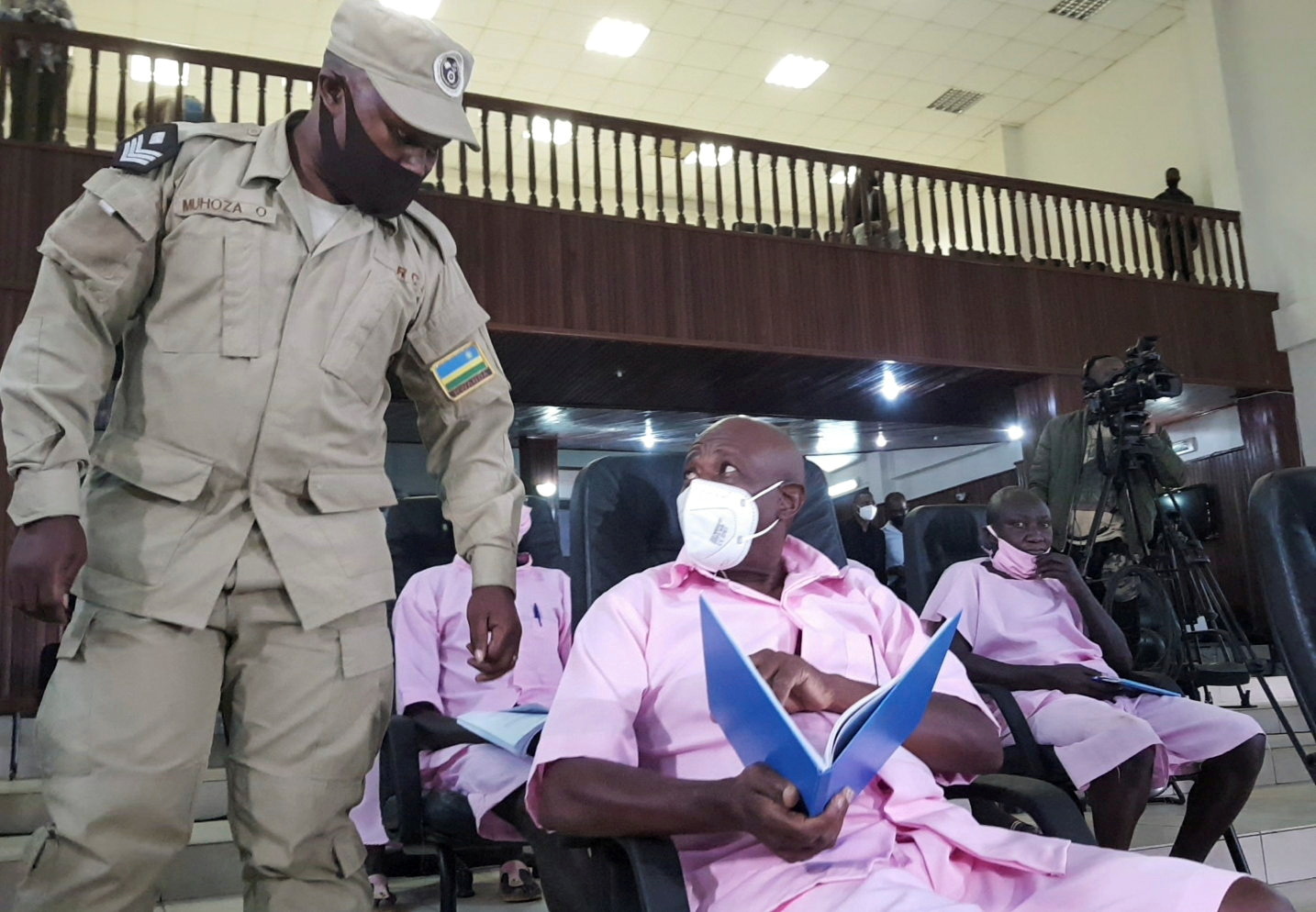 Paul Rusesabagina, portrayed as a hero in a Hollywood movie about Rwanda's 1994 genocide, talks to a prison guard inside the courtroom in Kigali