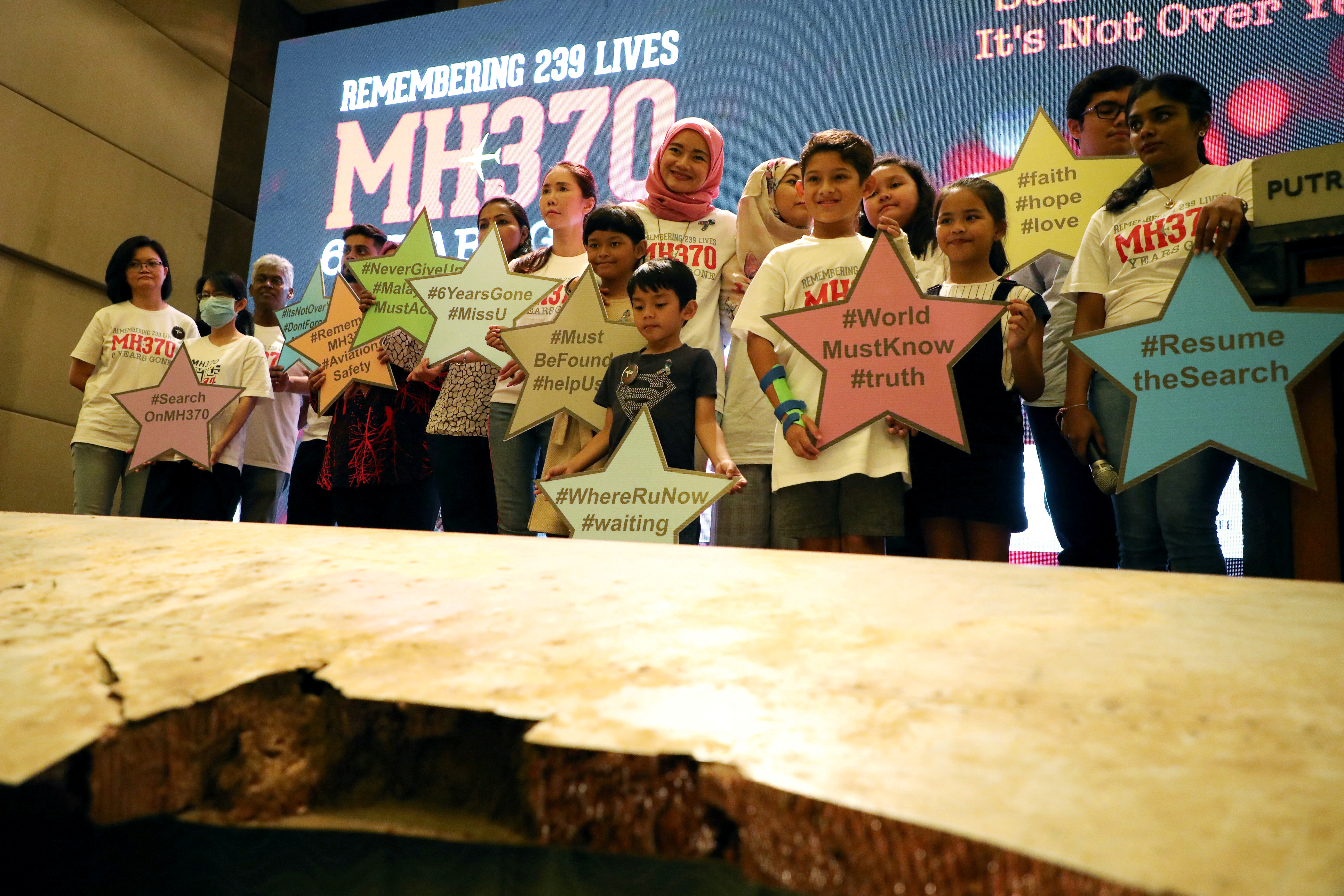 Family members of the victims pose for a group picture with a debris of the missing Malaysia Airlines flight MH370 during its sixth annual remembrance event in Putrajaya