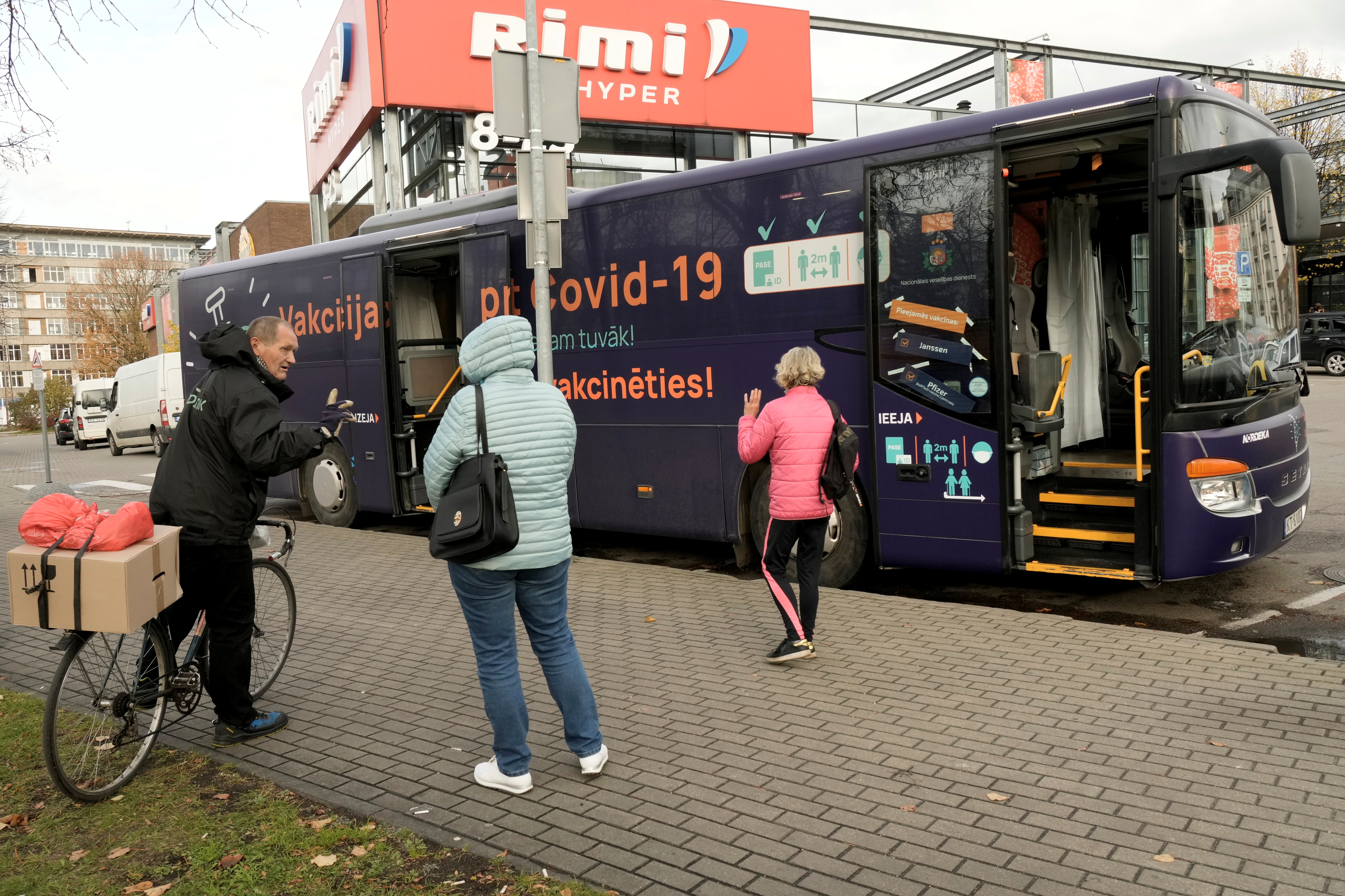 People wait to get inside a mobile coronavirus disease (COVID-19) vaccination bus next to the shopping center in Riga, Latvia October 19, 2021. Signs on a bus read 