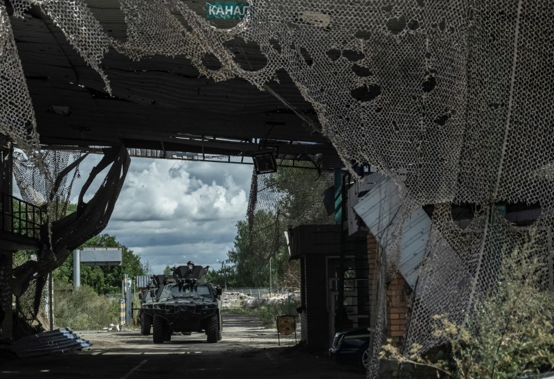 Ukrainian servicemen ride a military vehicle from a crossing point on the border with Russia in Sumy region