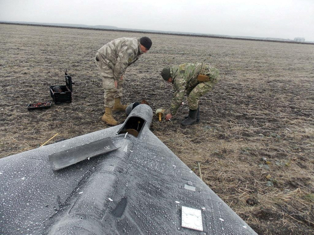 Members of police demining unit remove a warhead from a Russian kamikaze unmanned aerial vehicle landed by a radio electronic warfare during one of latest drone strikes in an unknown location in Ukraine