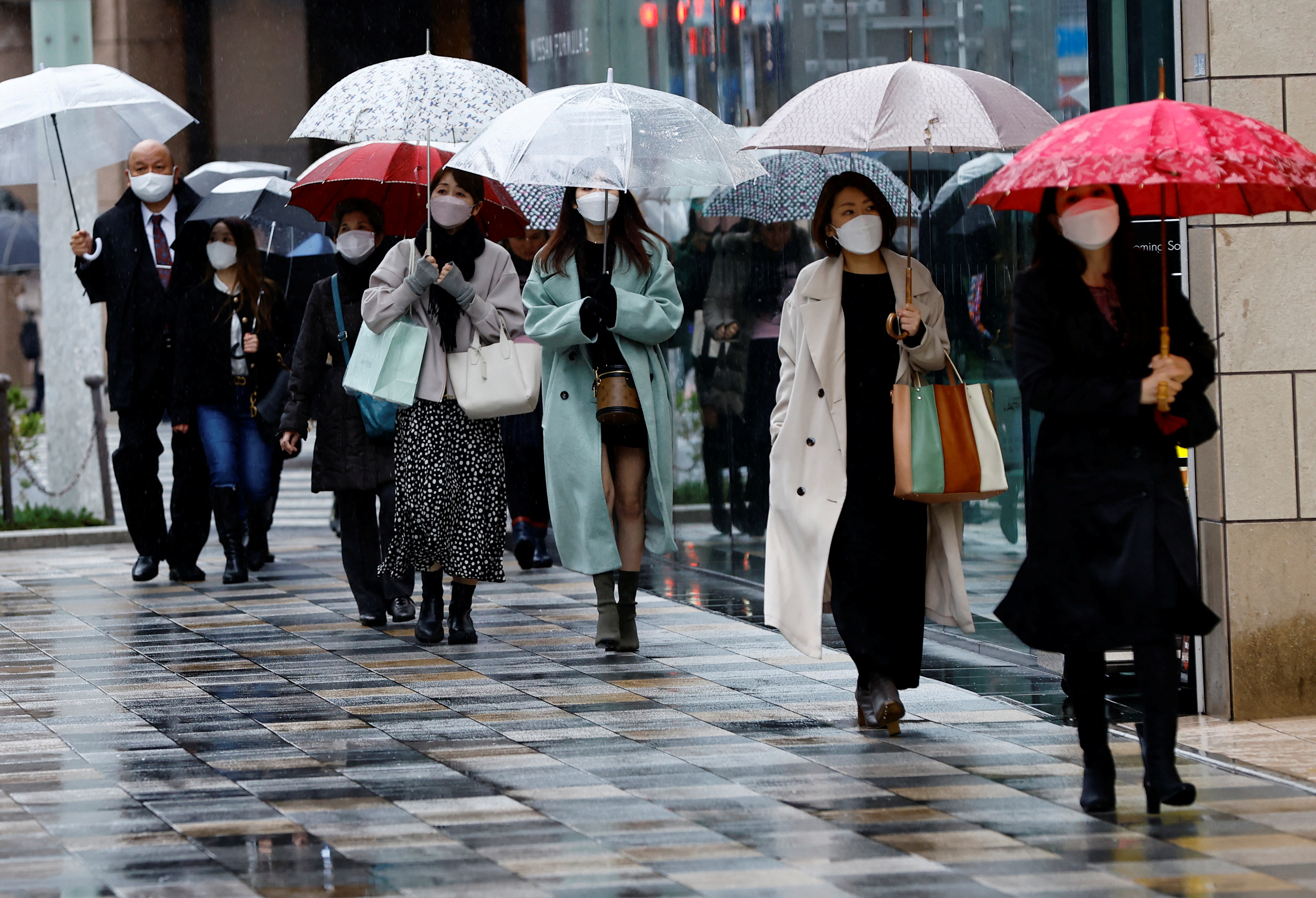 Pedestrians wearing protective face masks walk at a shopping district in Tokyo