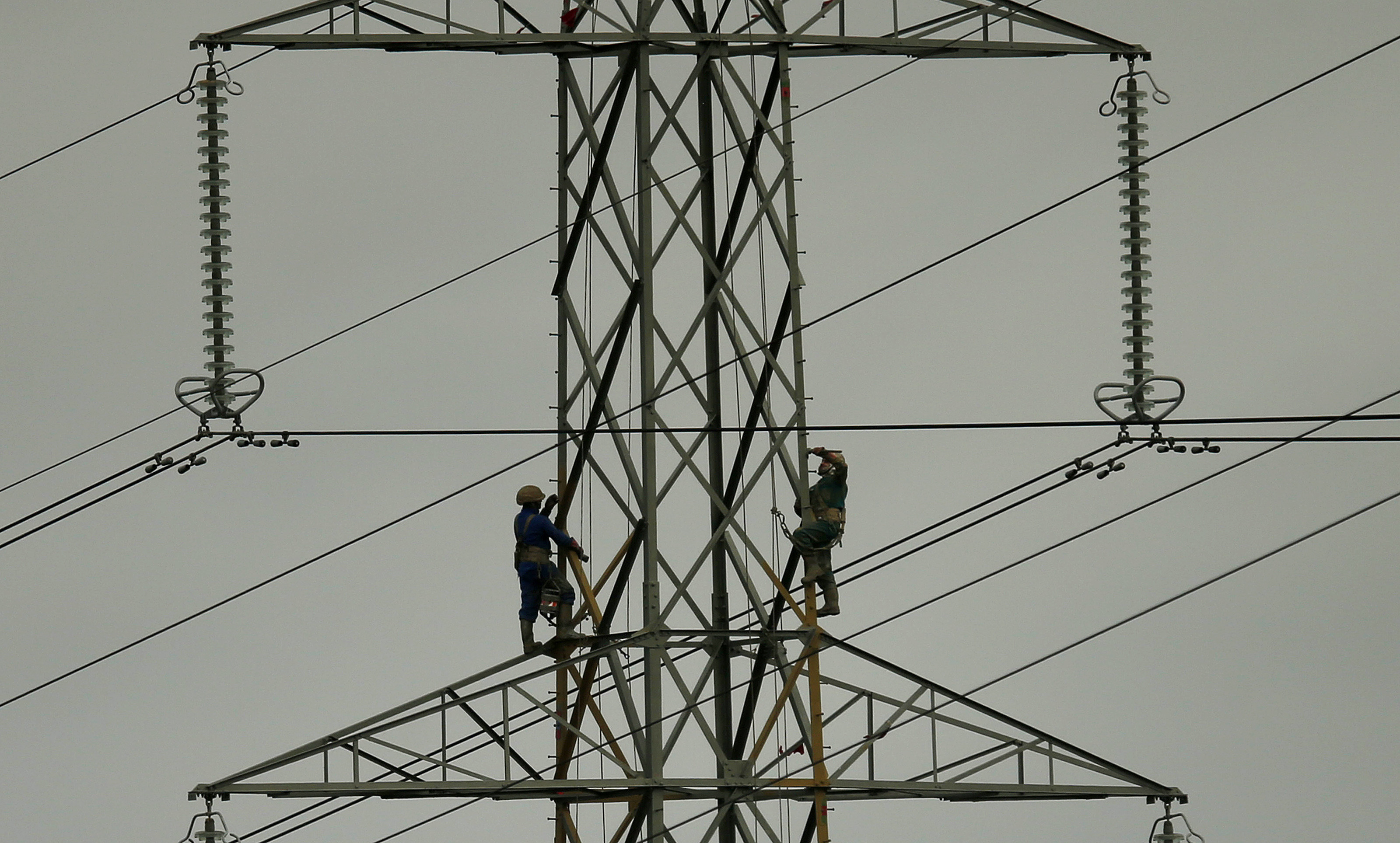 Workers paint an electricity pylon near Lymm, northern England February 18, 2015.  REUTERS/Phil Noble  