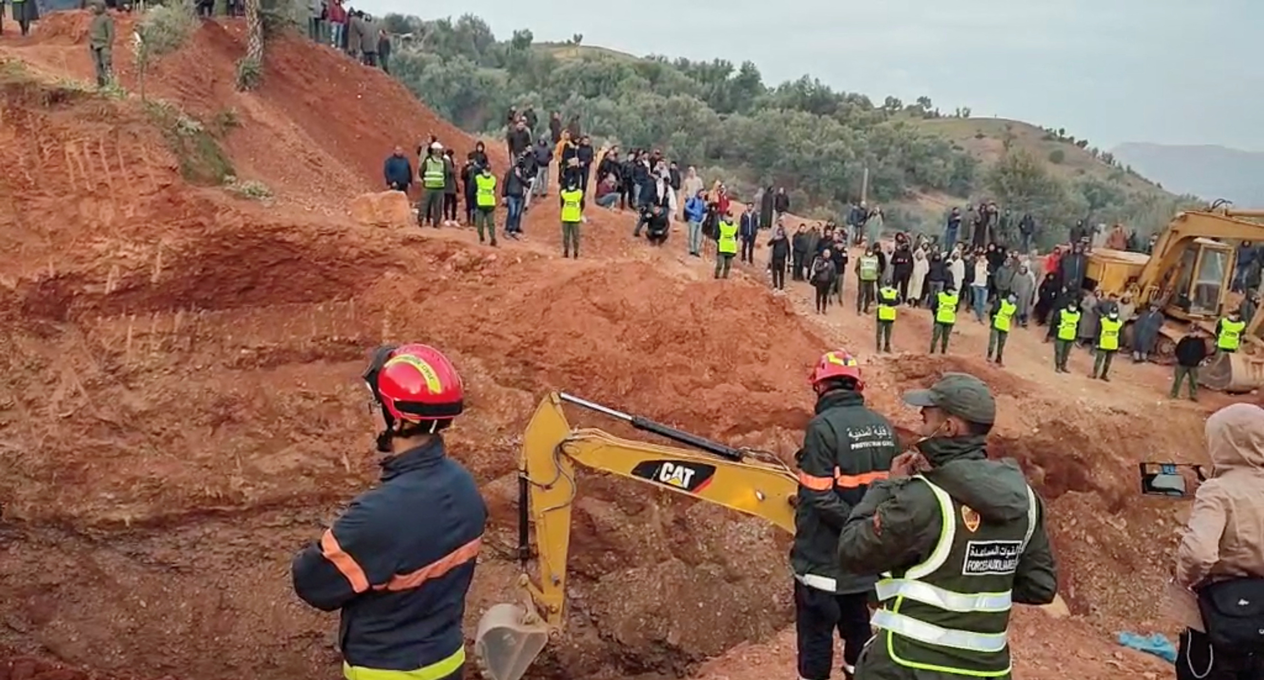 People use machinery to excavate the ground in order to free a boy trapped in an underground well, in Chefchaouen