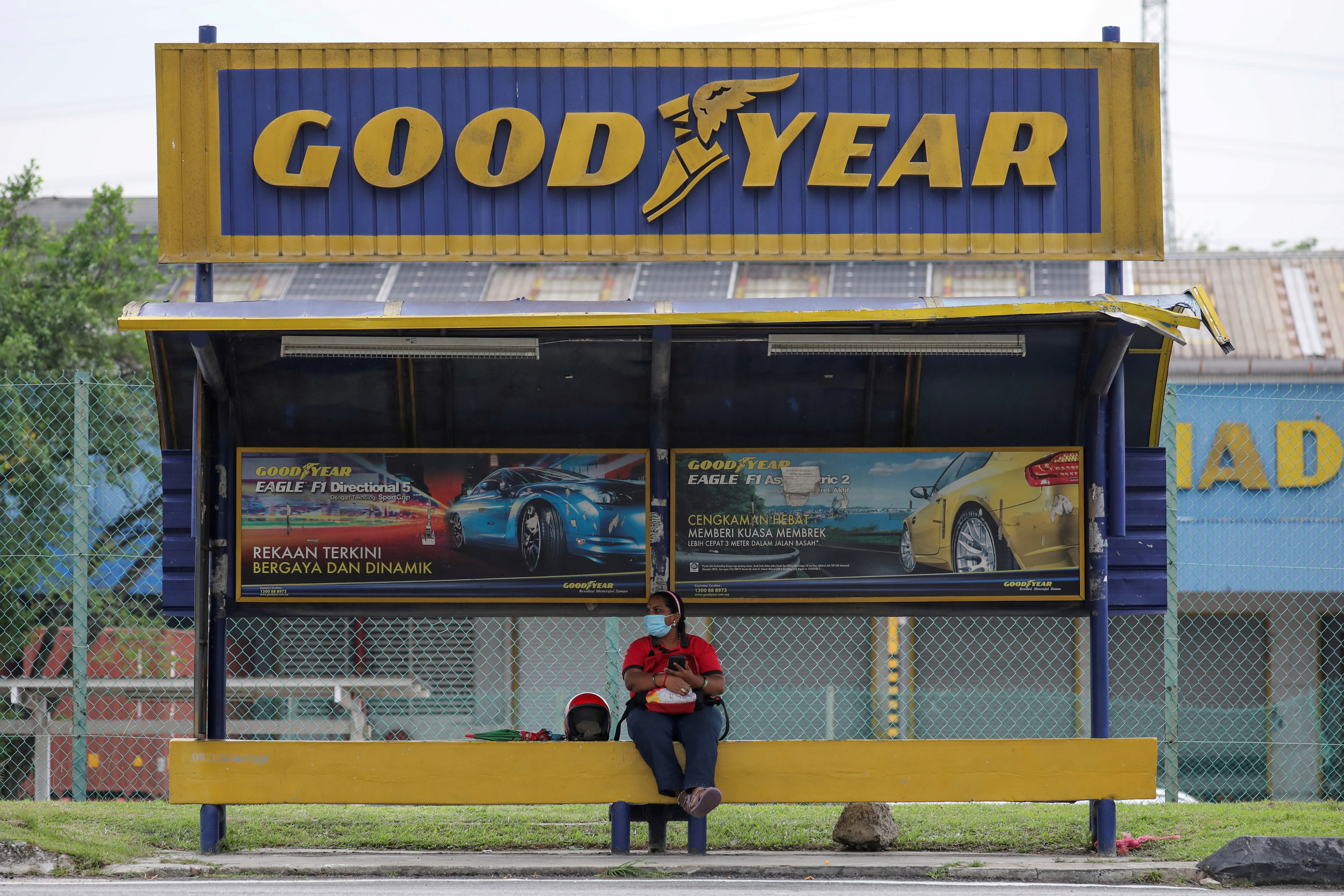 A woman sits at a bus stop outside Goodyear factory in Shah Alam