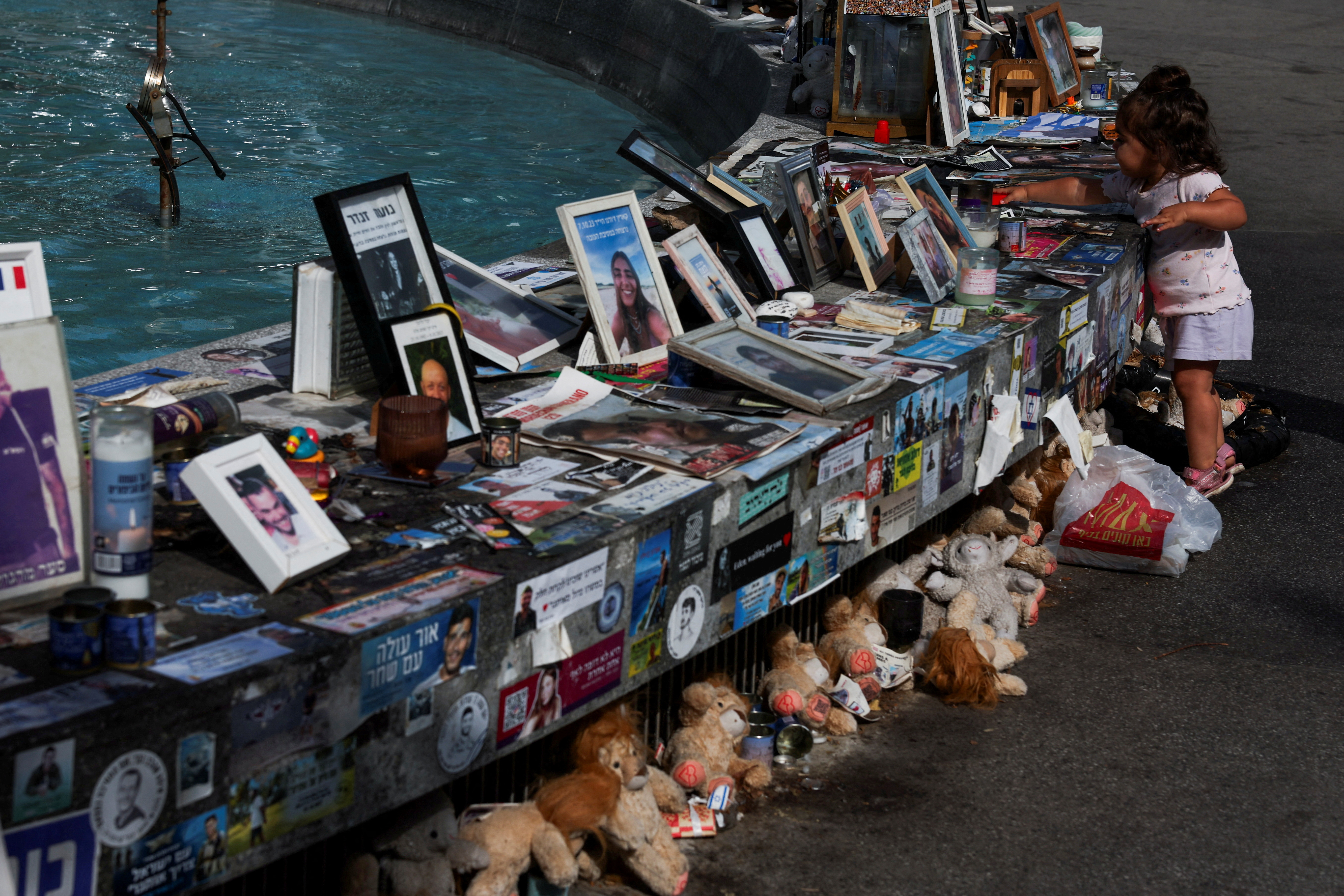 A child stands next to memorials for hostages, in Tel Aviv