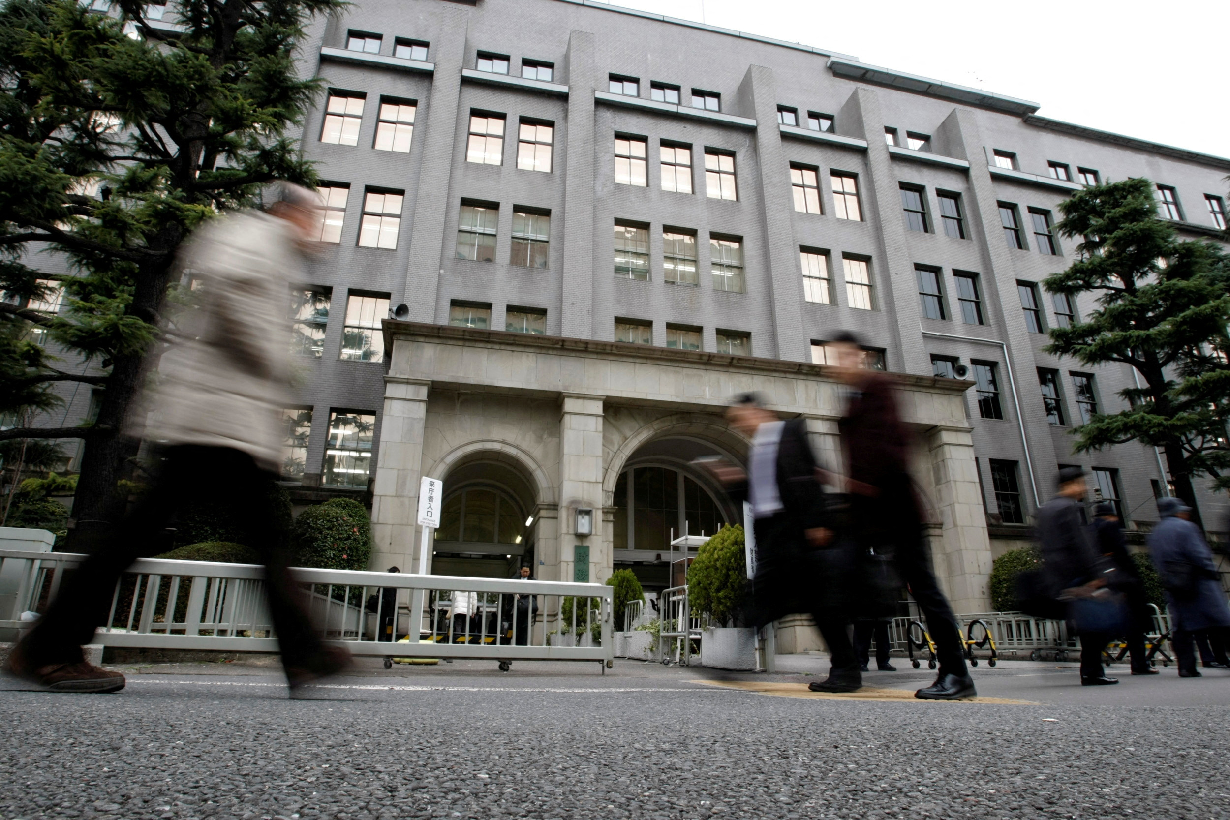 東京の財務省ビルの前を歩く歩行者