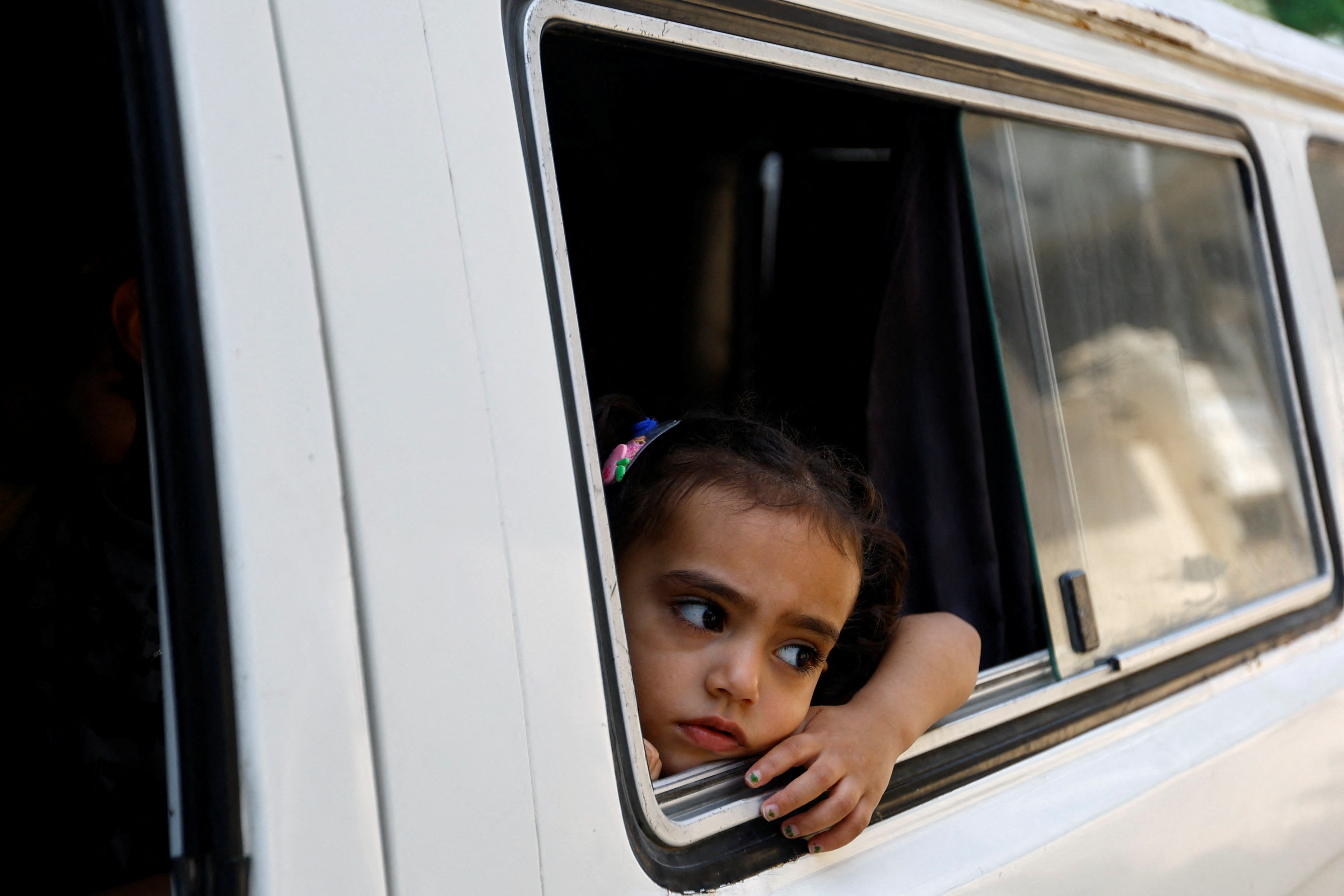 A Palestinian girl looks at a psychiatrist through an open van window in Deir al-Balah