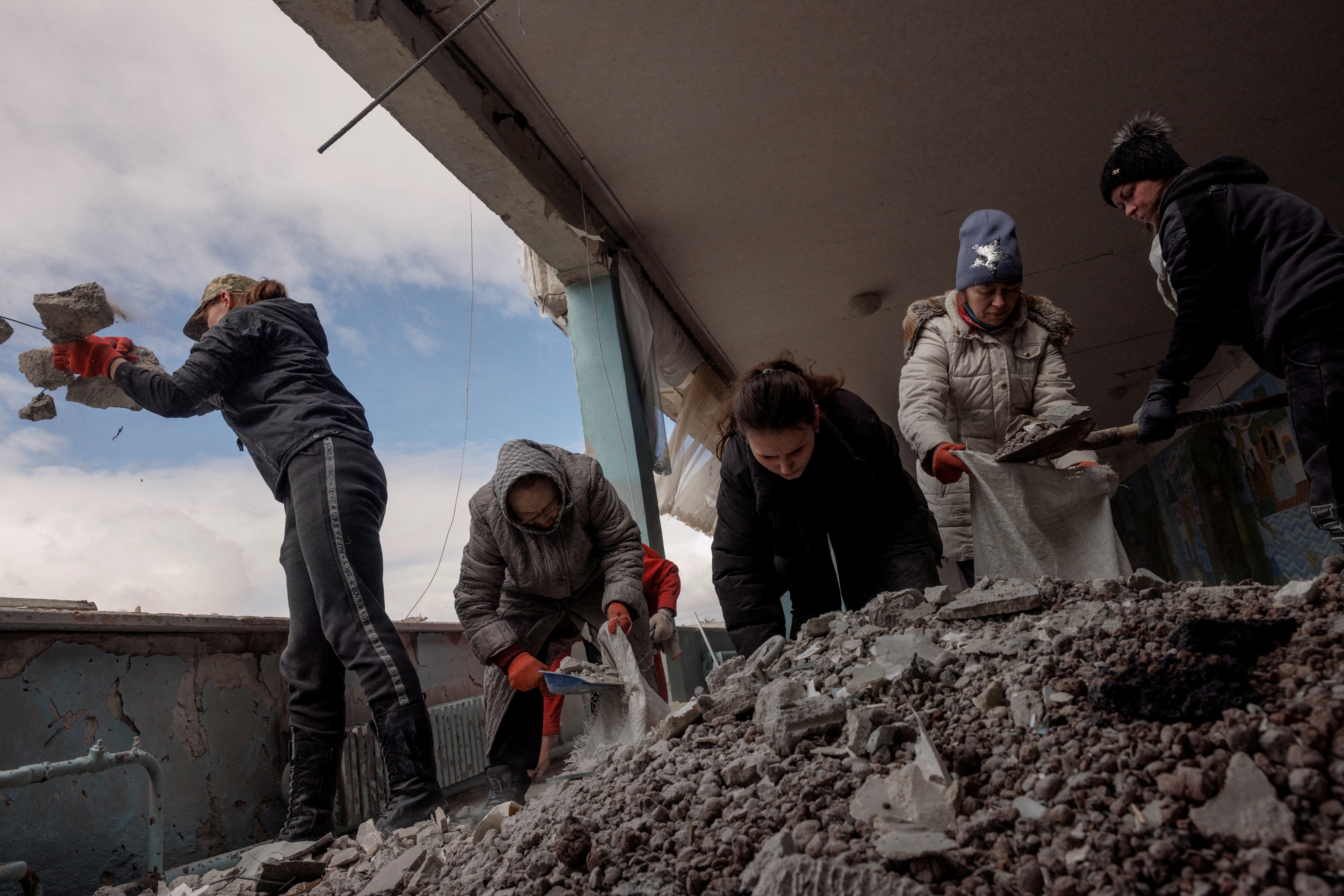 Women clear debris from a school that was damaged by shelling in Kharkiv as Russia's attack on Ukraine continues, Ukraine