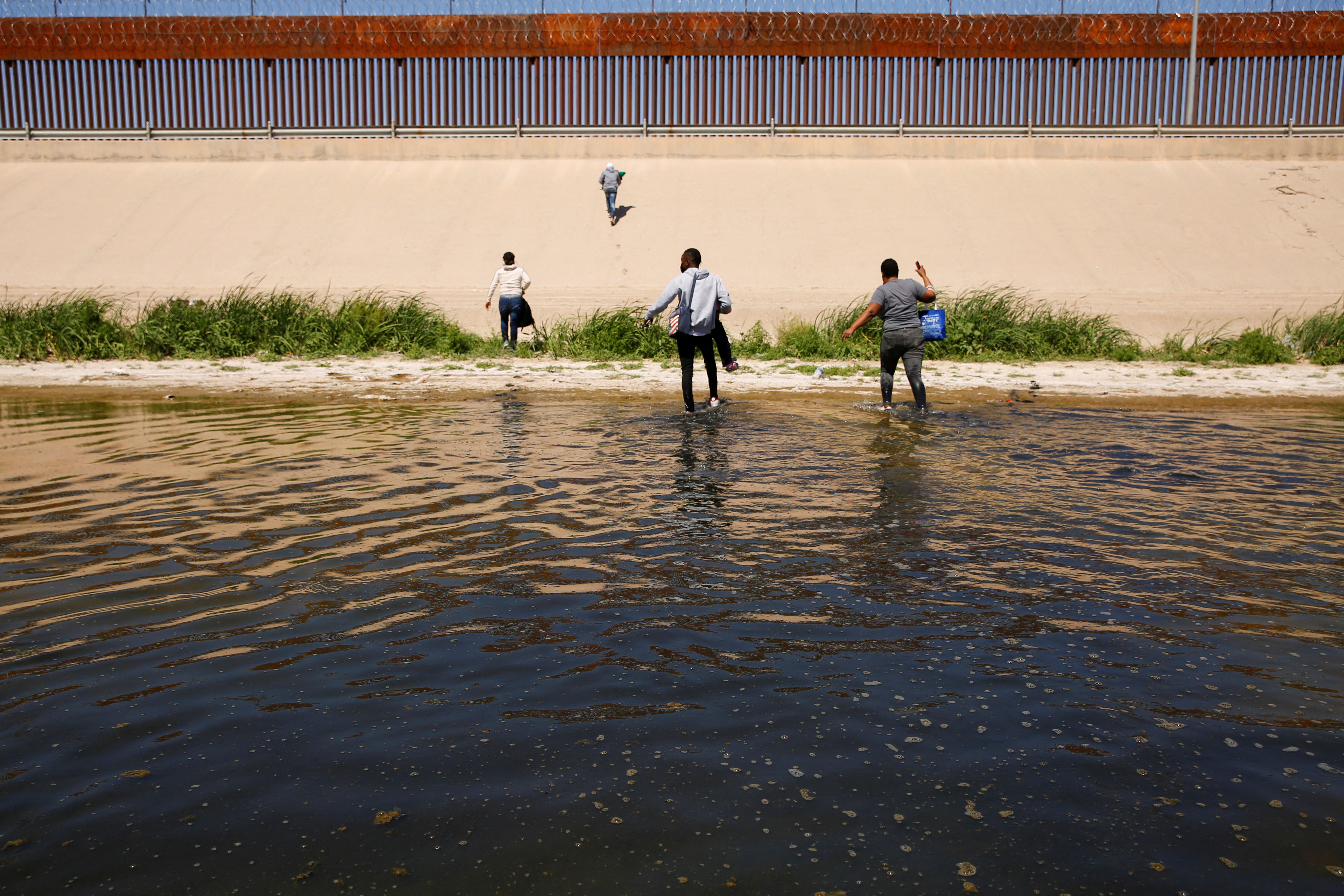 FILE PHOTO - Asylum-seeking migrants walk out of the Rio Bravo river after crossing it, in El Paso