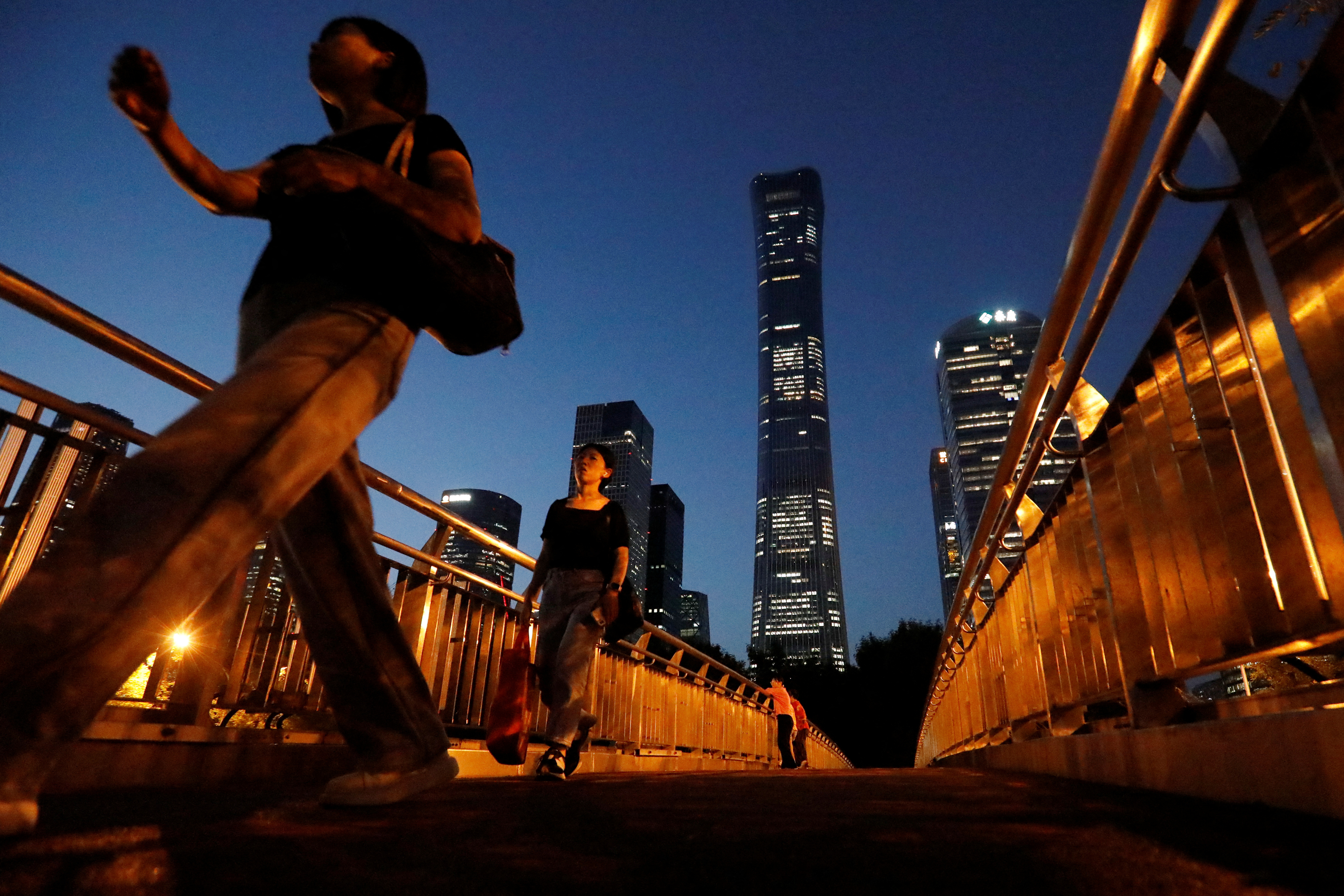 Pedestrians walk on an overpass near skyscrapers at the Central Business District in Beijing
