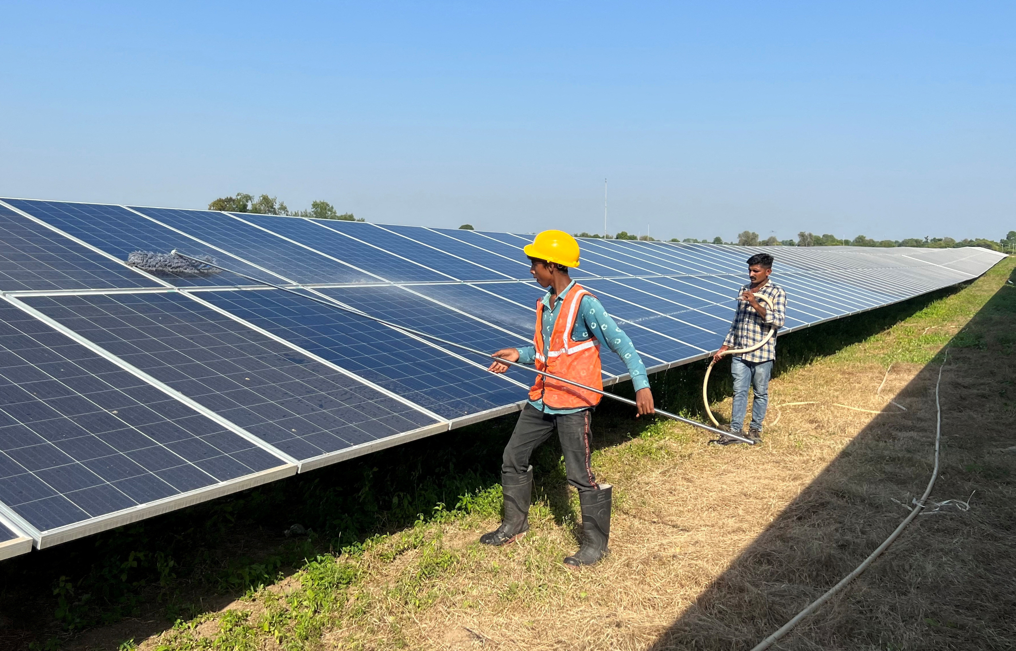 Workers clean panels at a solar park in Modhera