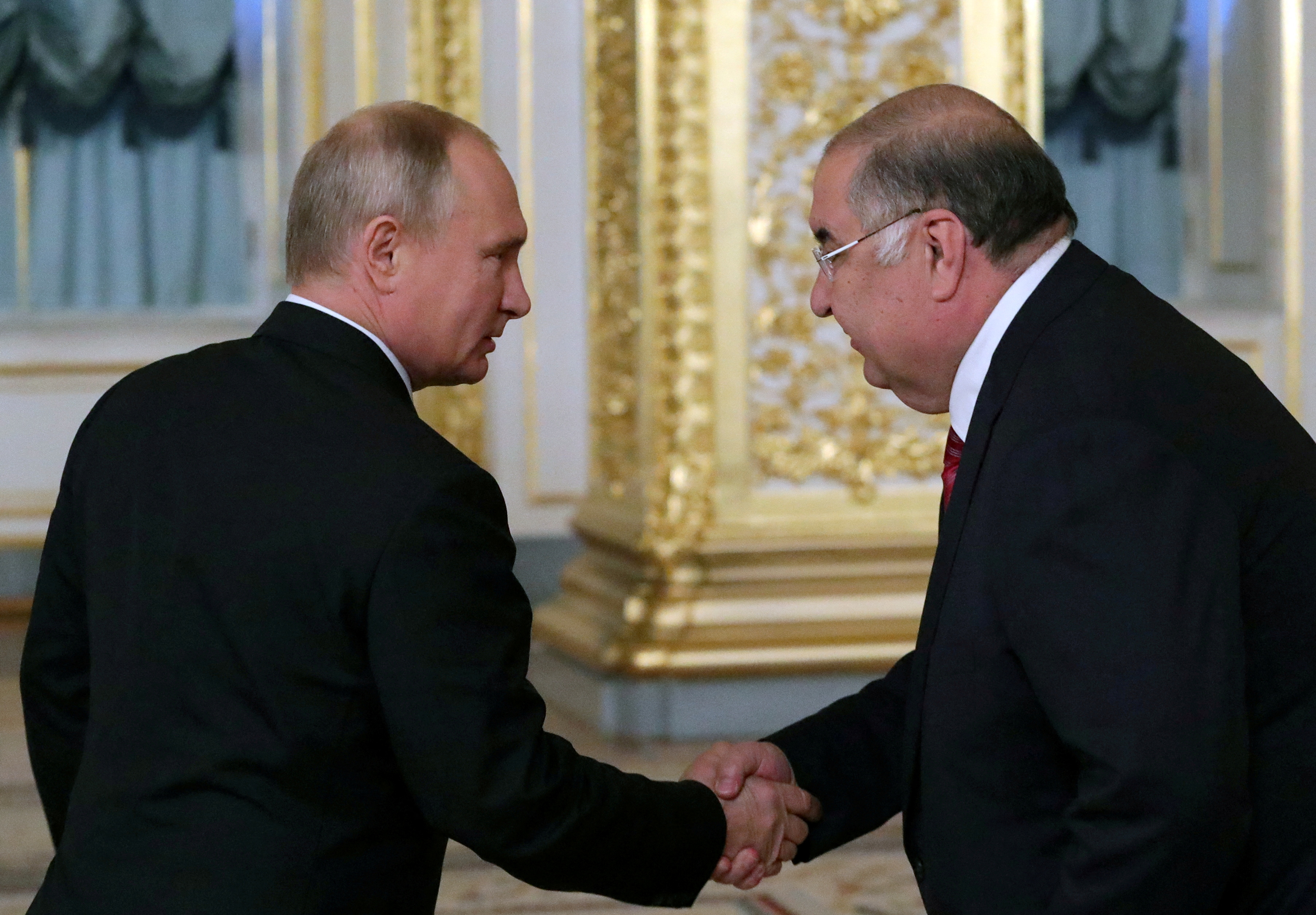 Russian President Putin shakes hands with billionaire Usmanov before a meeting with Italian businessmen in Moscow