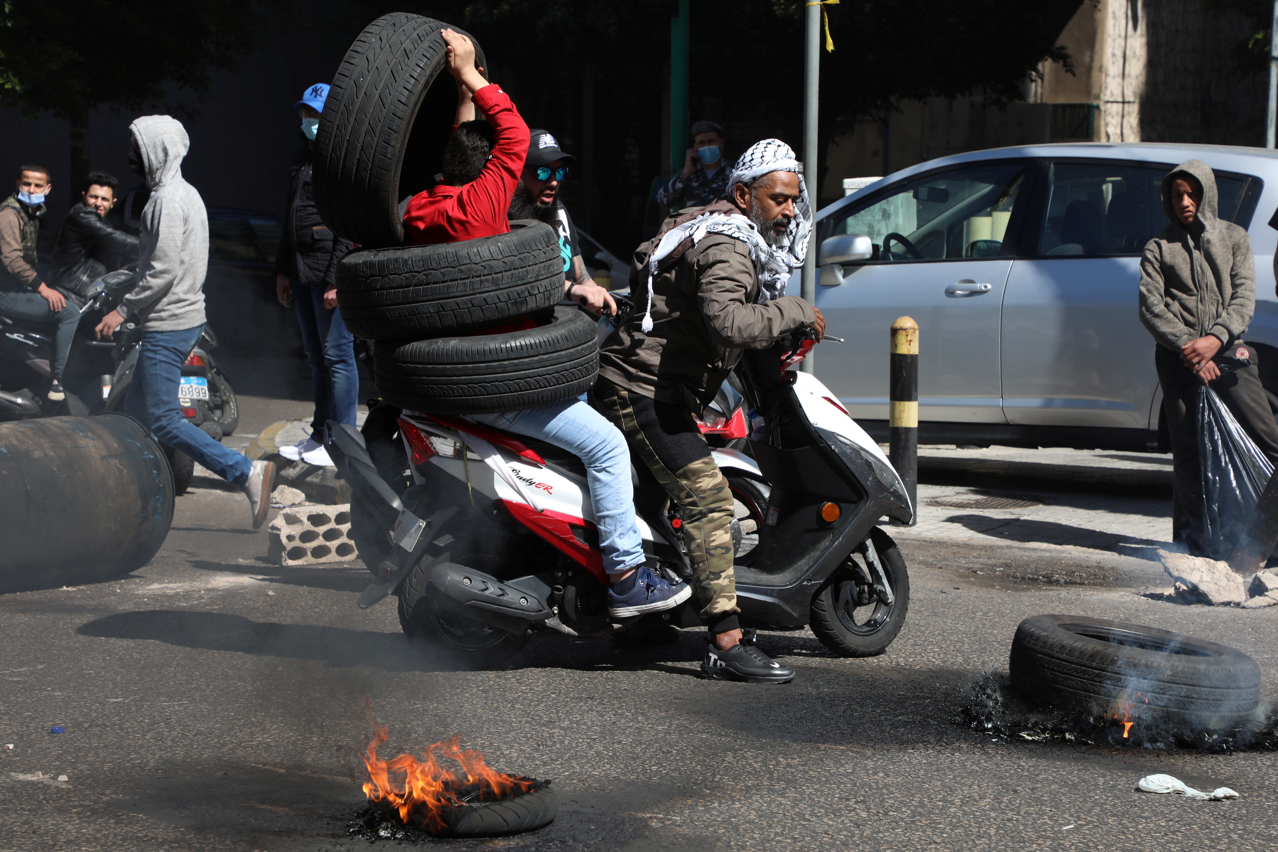 Demonstrators attempt to block a road with tires, during a protest against the fall in Lebanese pound currency and mounting economic hardships, in Beirut, Lebanon March 16, 2021. REUTERS/Mohamed Azakir