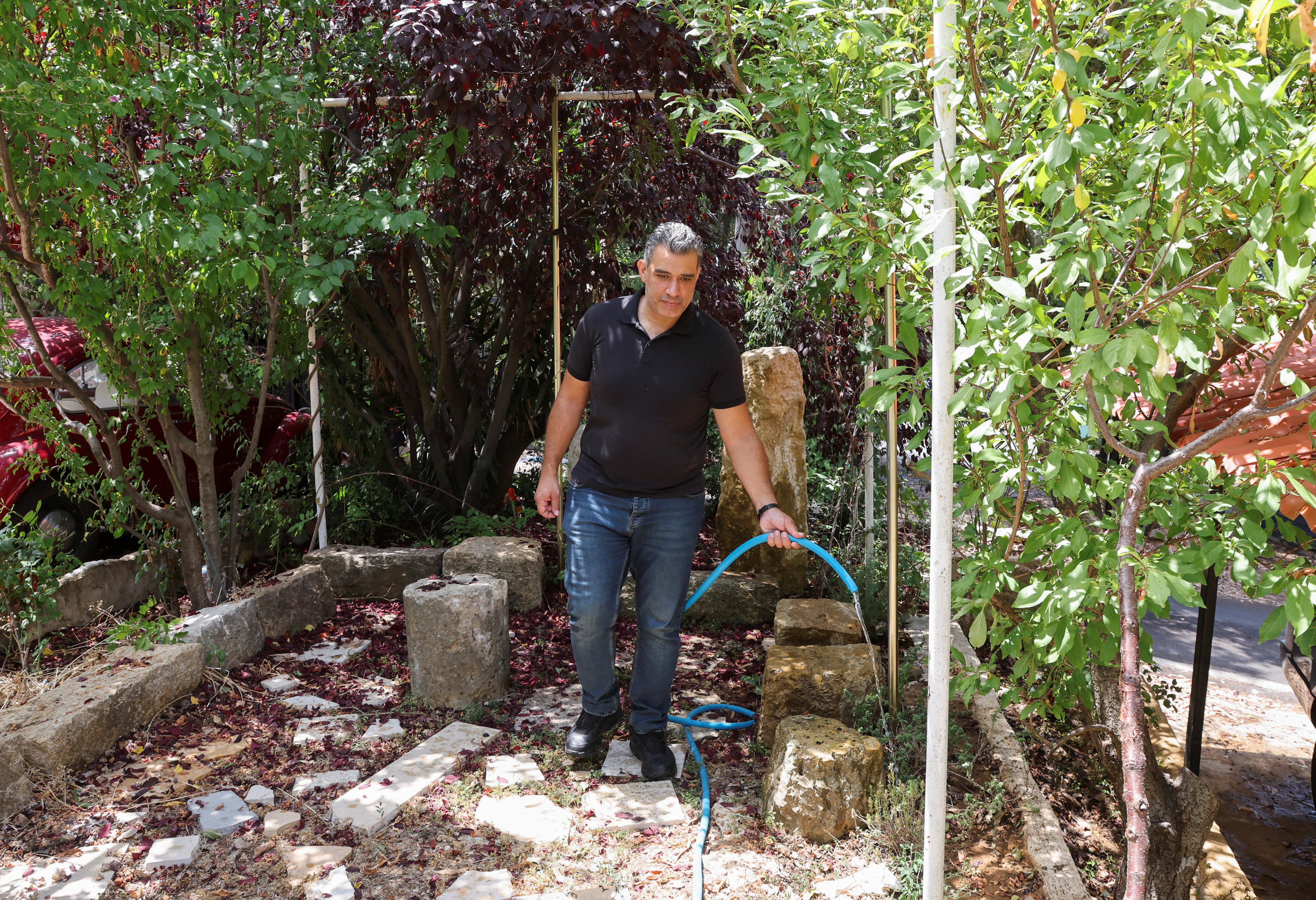 Walid Chaar, an employee at the Lebanese Finance Ministry, waters the garden at his home in Ainab