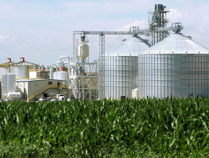 An ethanol plant with its giant corn silos next to a cornfield