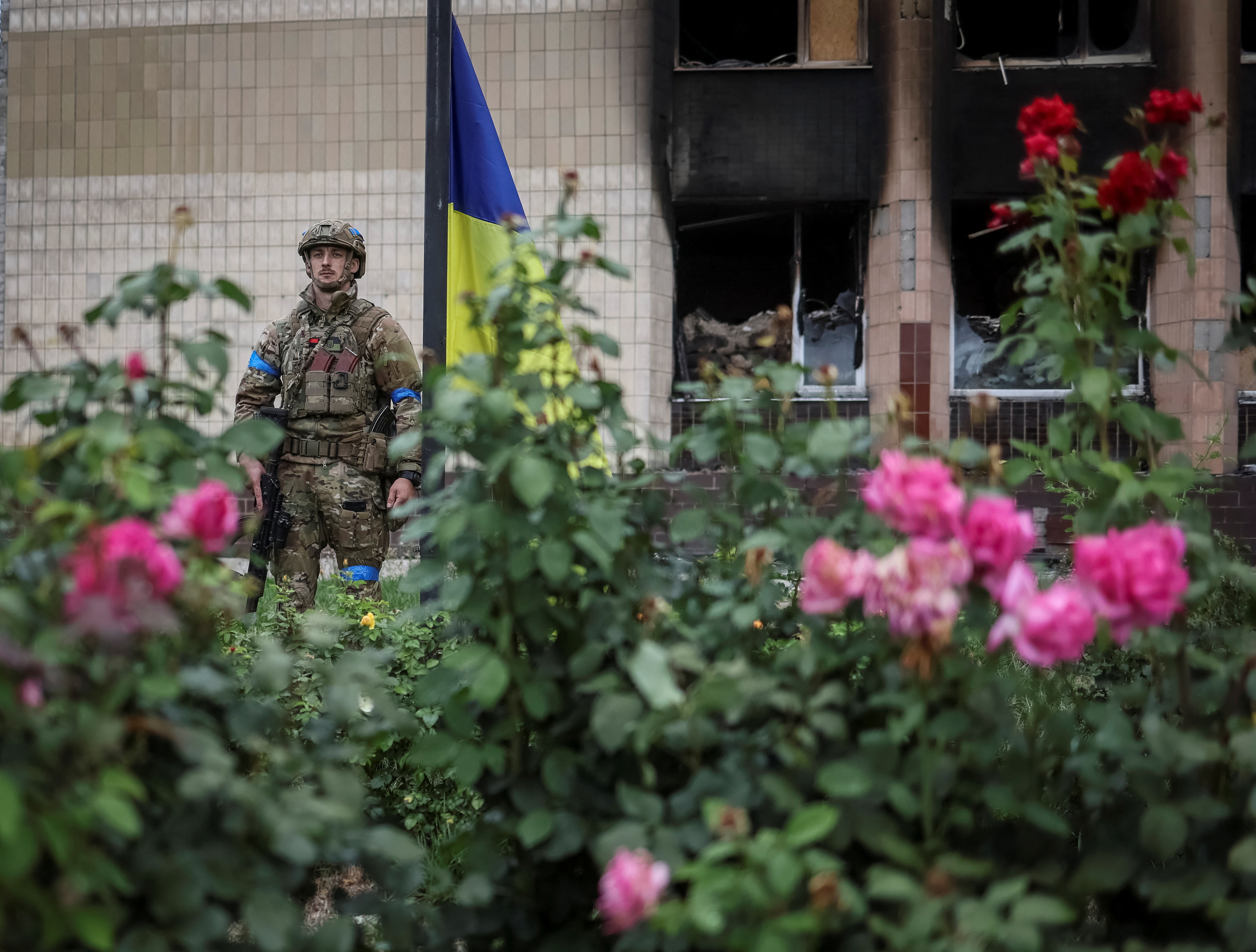 Ukrainian serviceman attends a national flag raising ceremony in the town of Izium