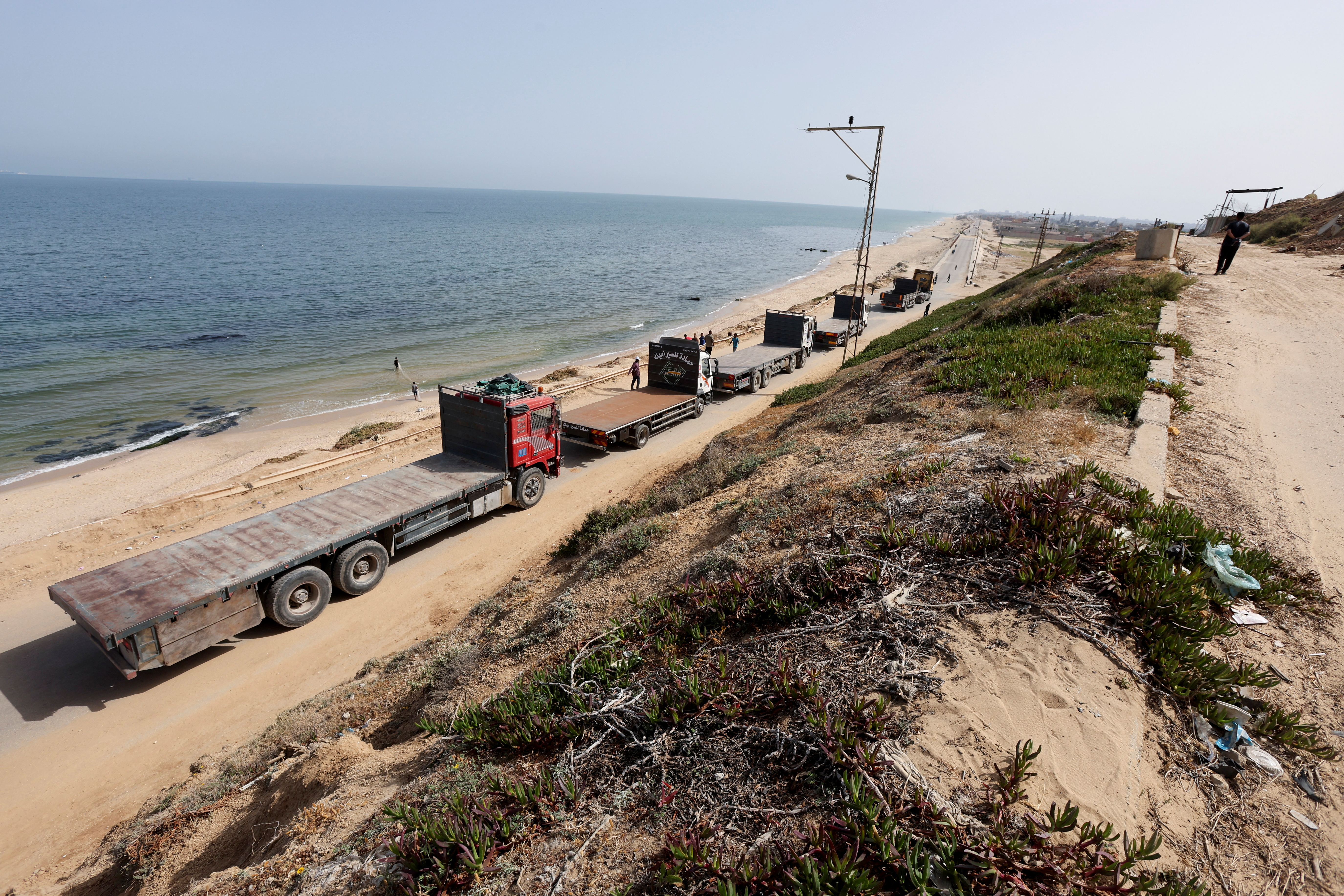 Trucks move towards a U.S.-built pier where they will be loaded with aid, as seen from central Gaza Strip