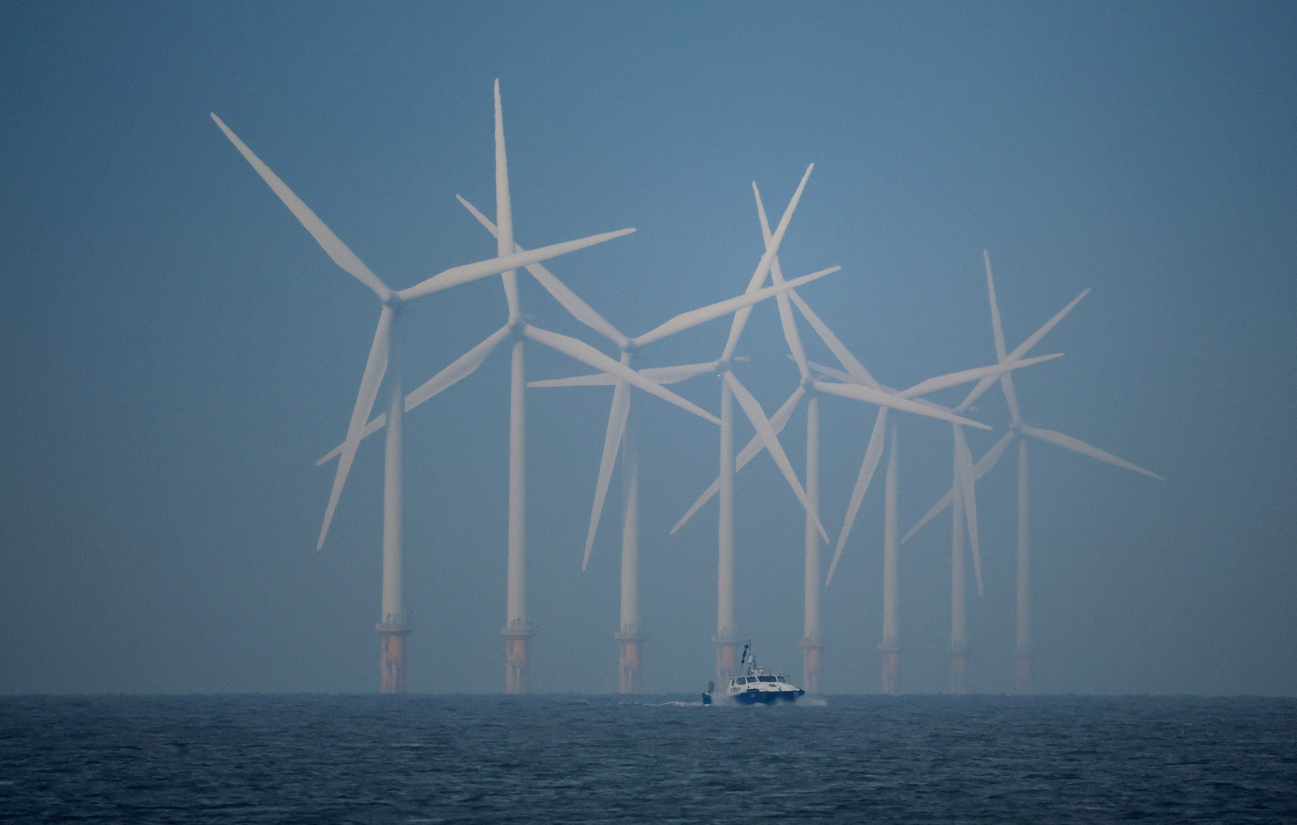 A survey vessel sails past wind turbines at the Burbo Bank offshore wind farm near New Brighton