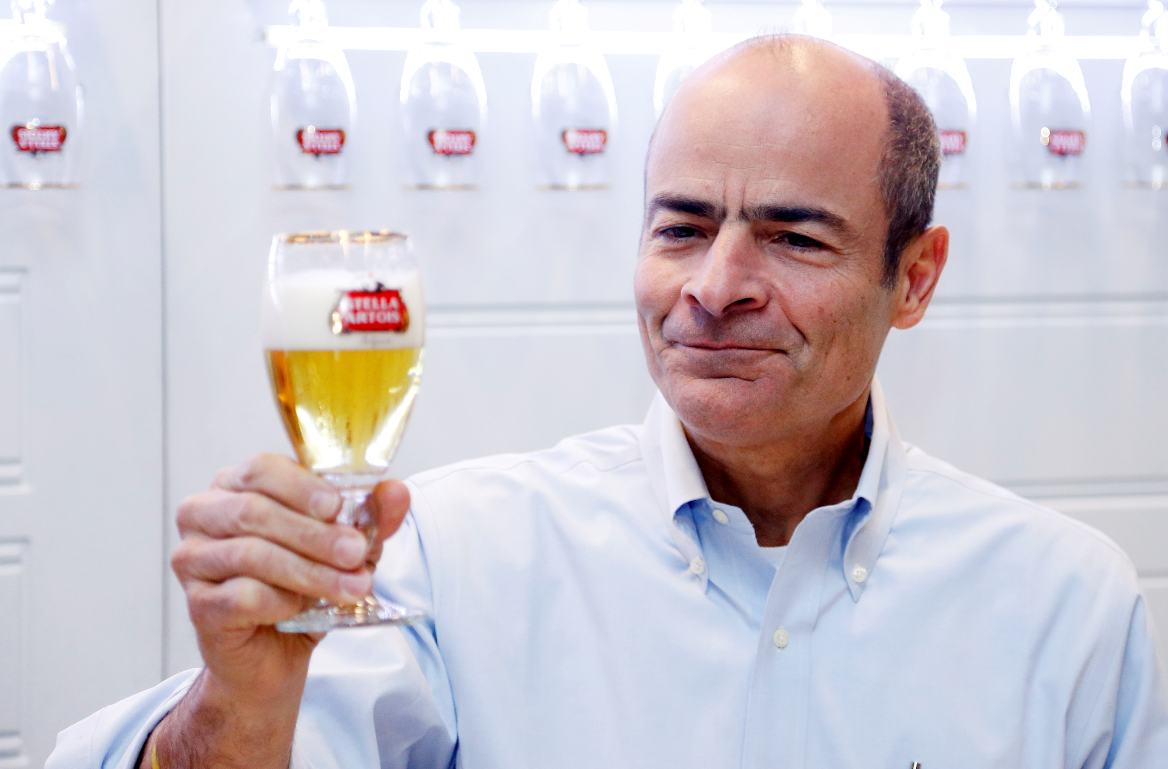 Anheuser-Busch InBev CEO Brito poses with a Stella Artois beer after a news conference in Leuven