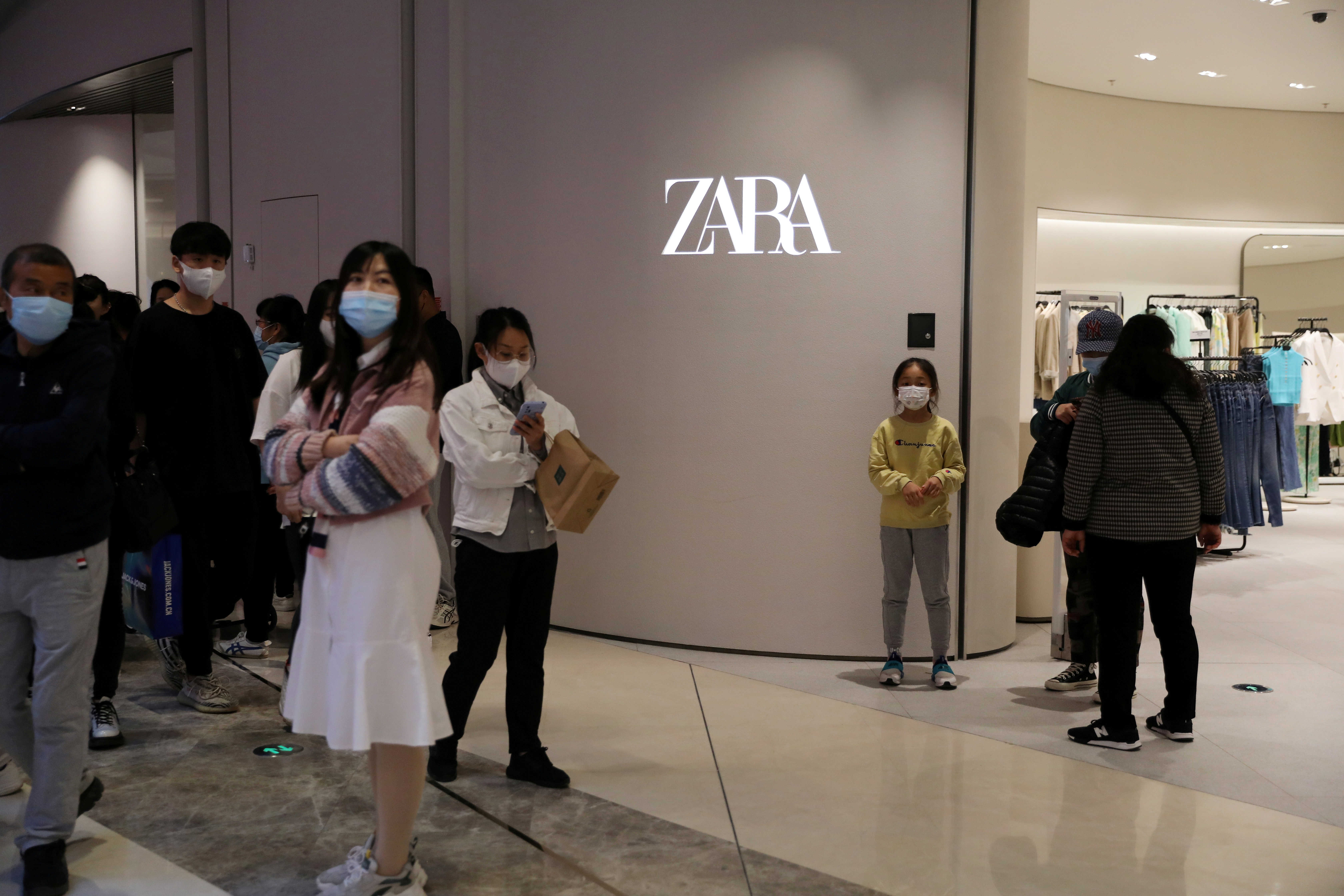 Shoppers walk past a clothing store of Inditex's Zara brand at a newly opened shopping mall in Beijing, China April 16, 2021. REUTERS/Tingshu Wang/File Photo