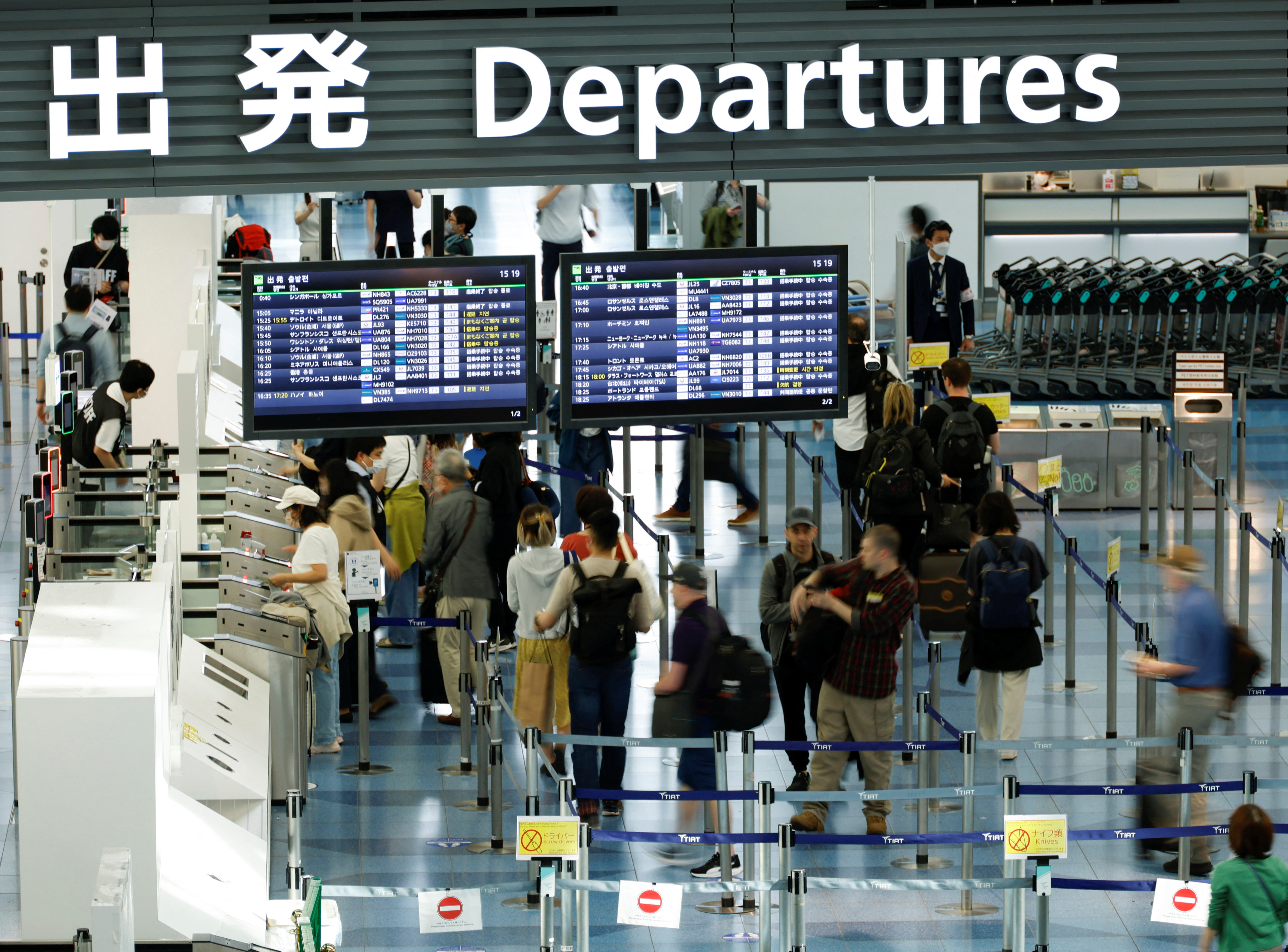Passengers stand in an international flight departure lobby at Tokyo International Airport
