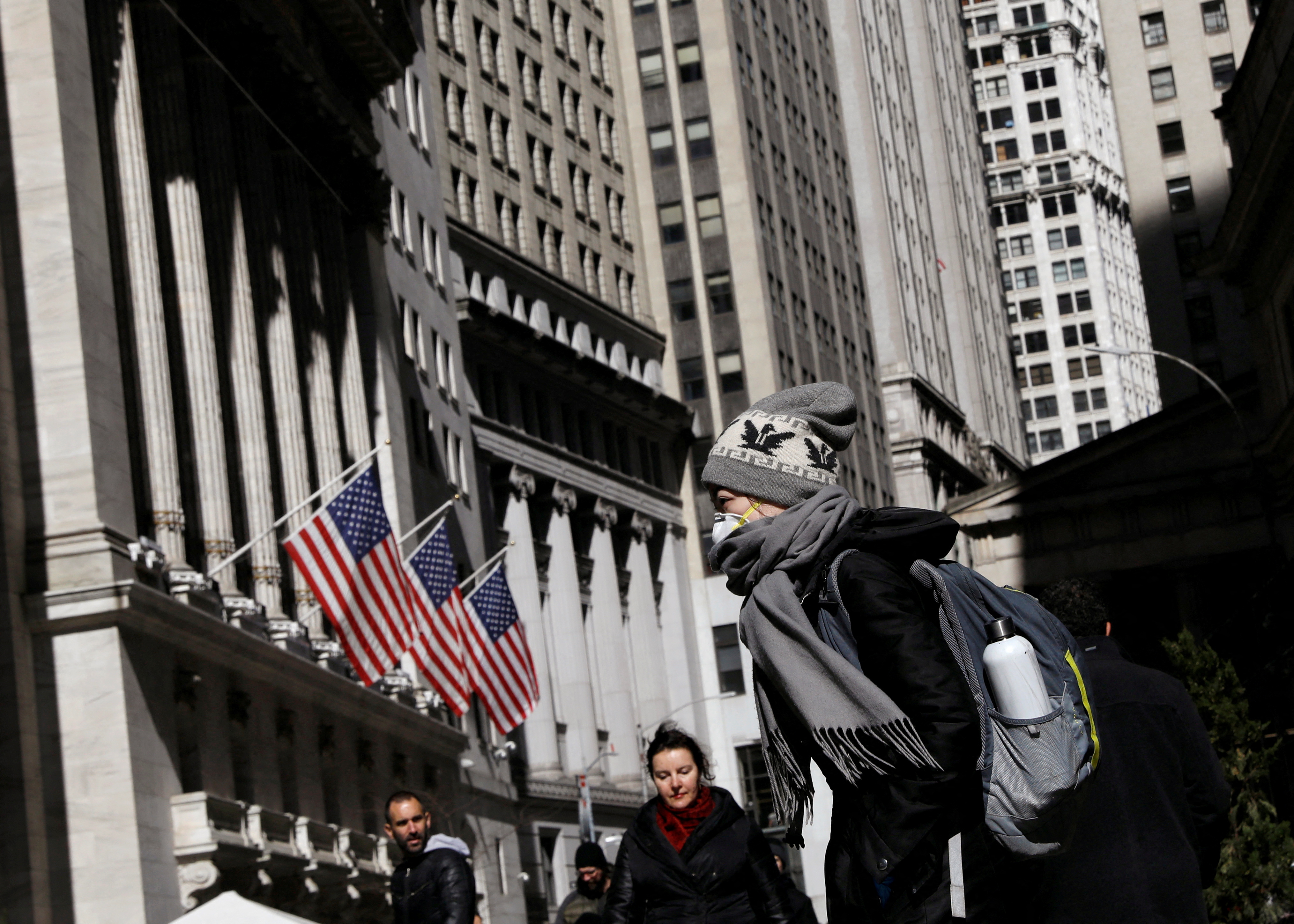 A woman wears a mask near the New York Stock Exchange (NYSE) in the Financial District in New York, U.S., March 4, 2020. REUTERS/Brendan McDermid/File Photo