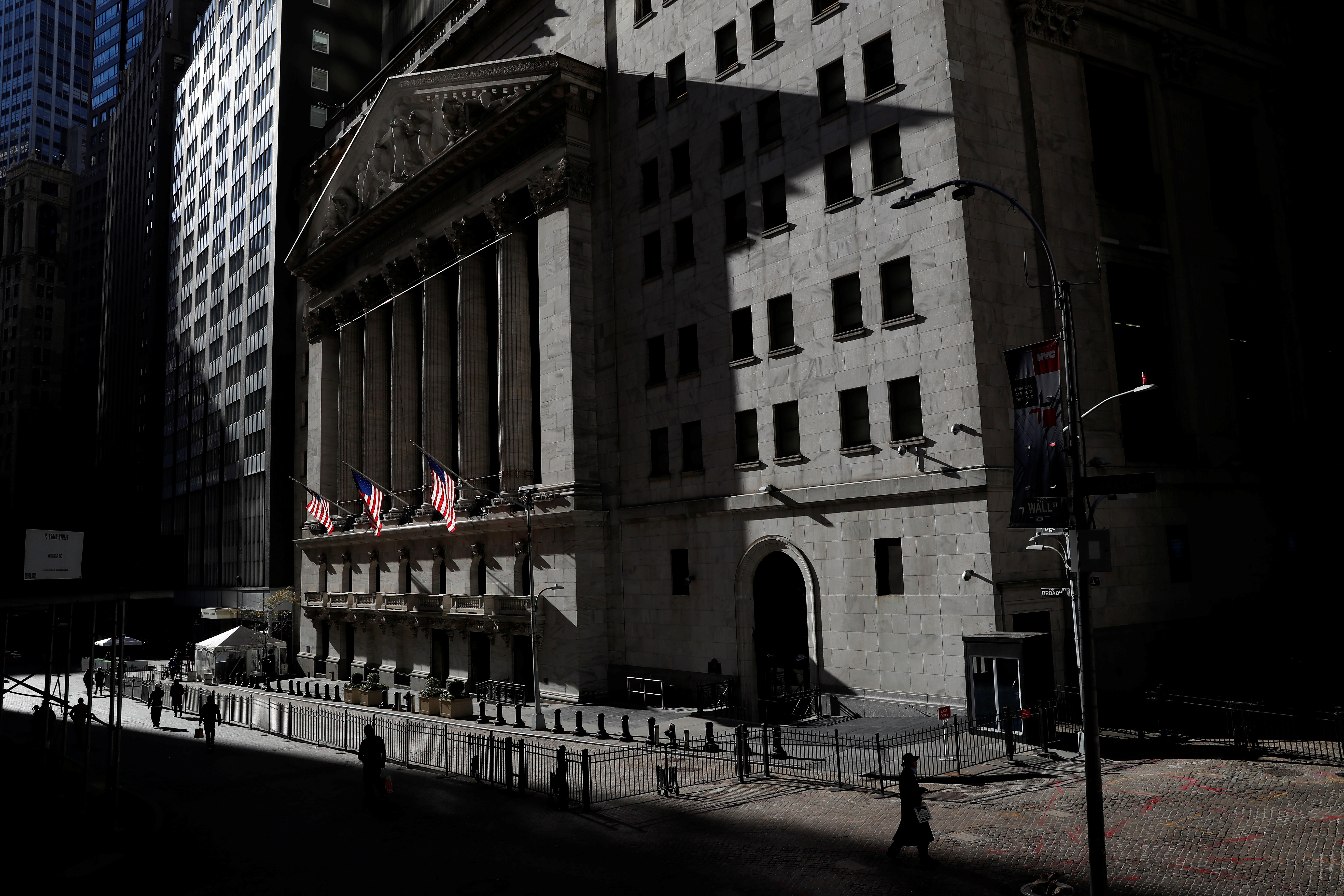 The New York Stock Exchange (NYSE) is seen as people walk in silhouette in the financial district of New York