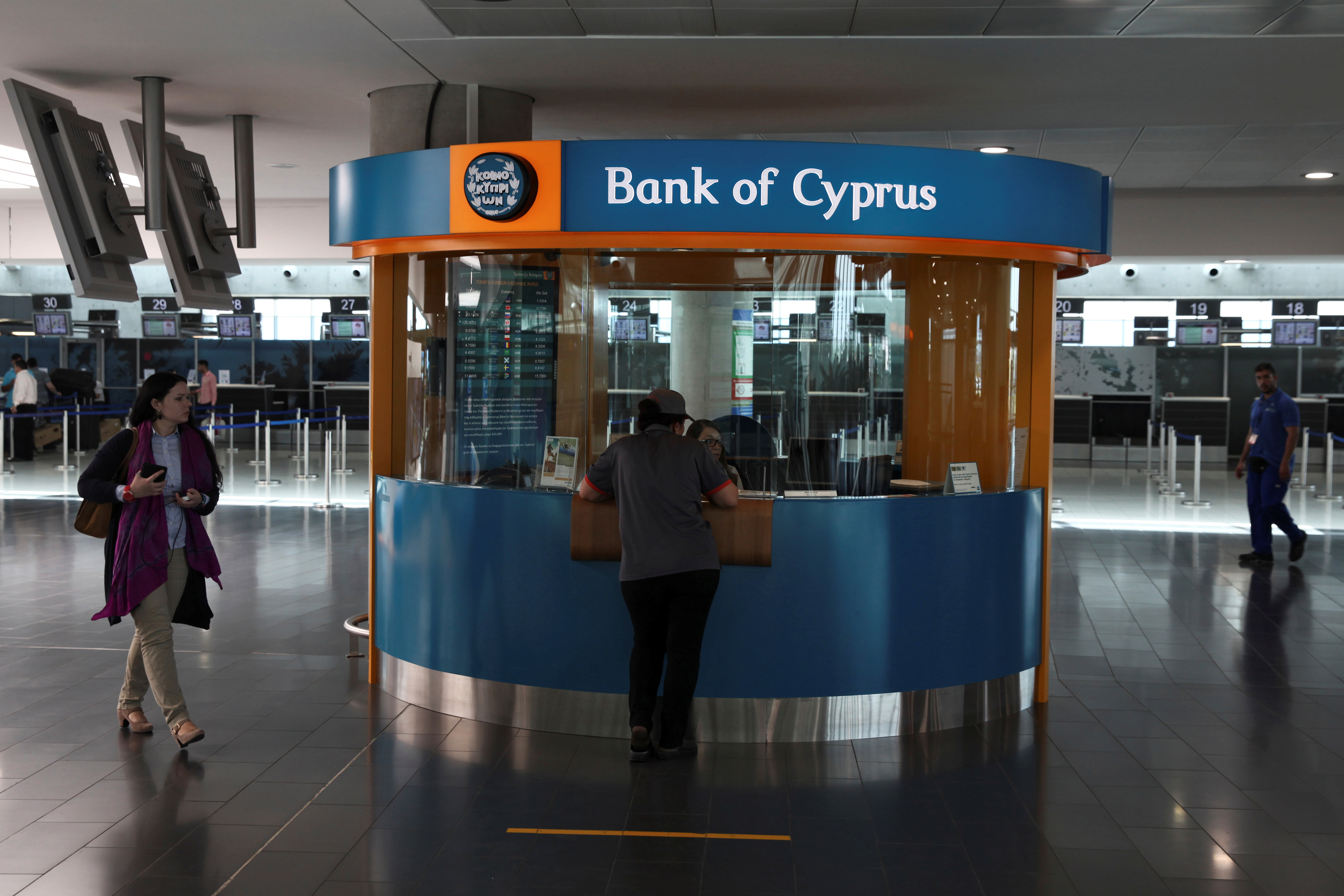 A passenger makes a transaction at a branch of Bank of Cyprus at the departures building of Larnaca Airport in Larnaca