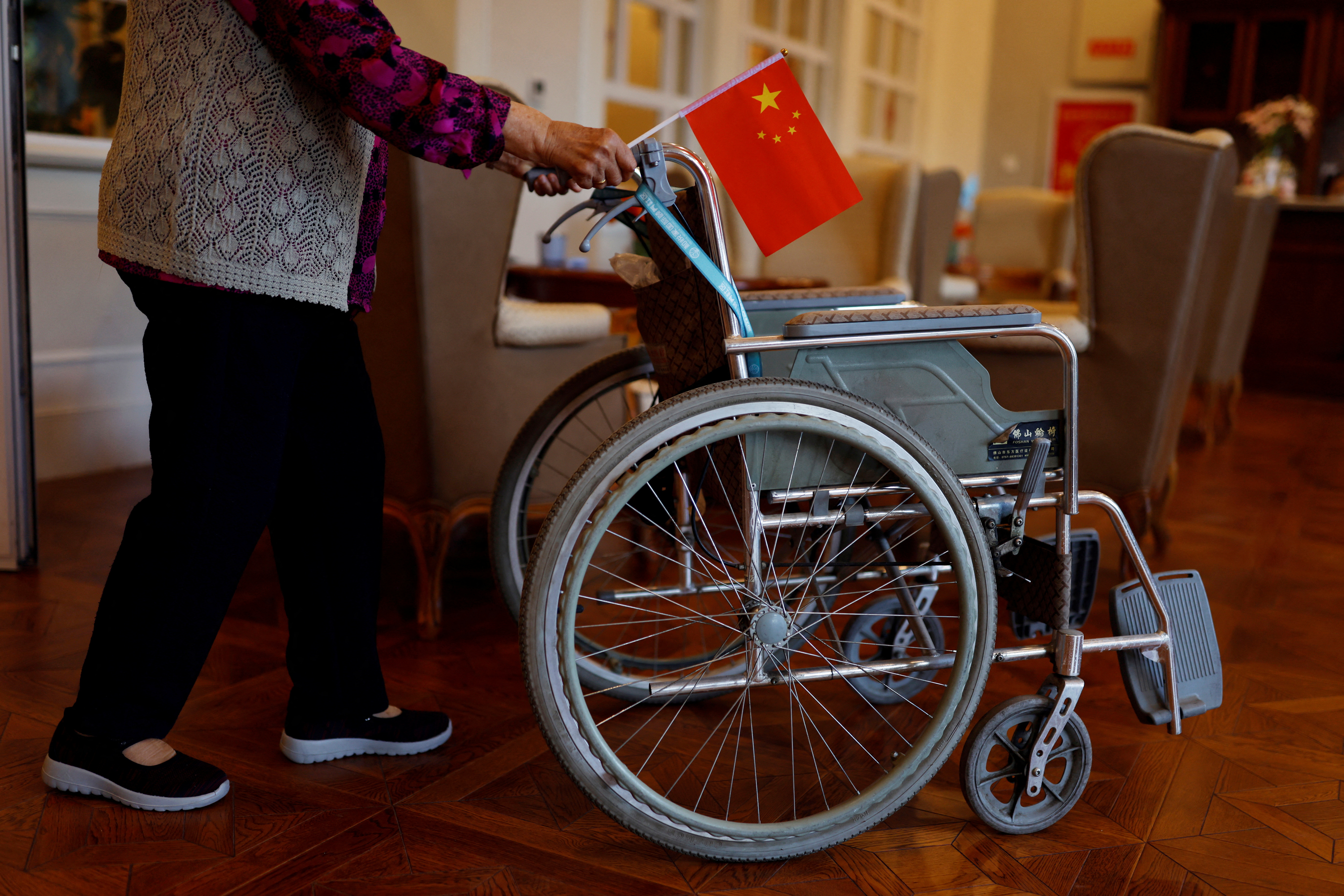 Resident pushes a wheelchair while holding a Chinese national flag at a care home for the elderly, in Beijing