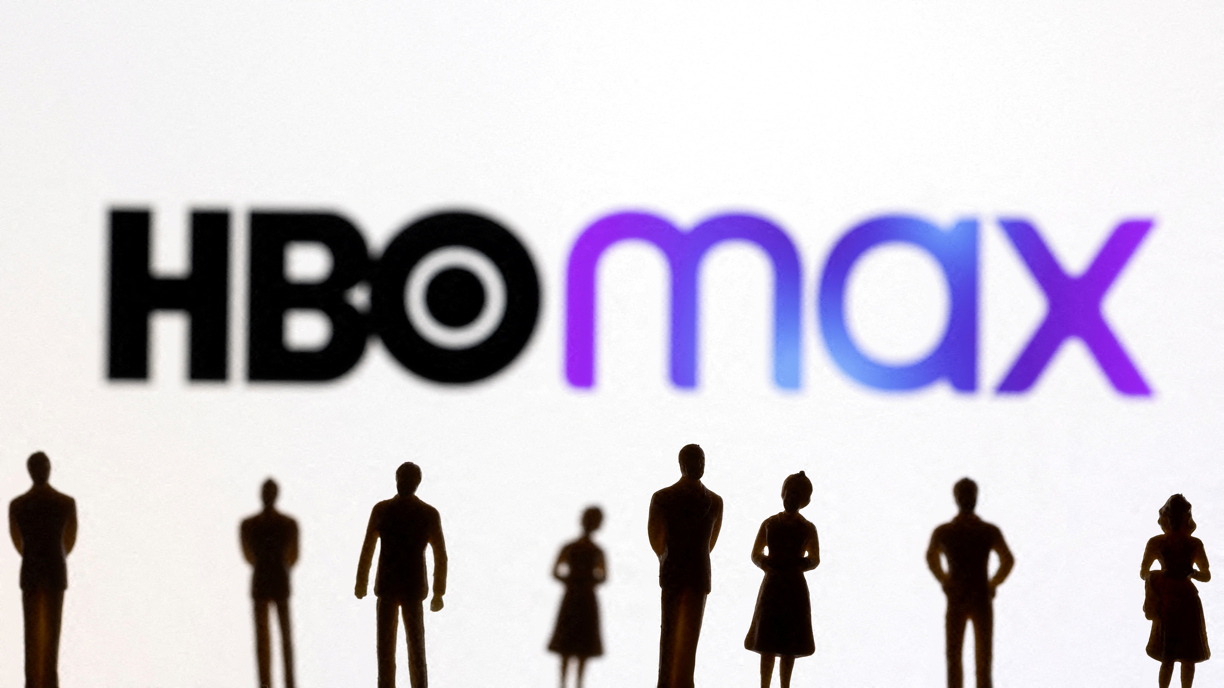 Toy figures of people are seen in front of the displayed HBO Max logo, in this illustration
