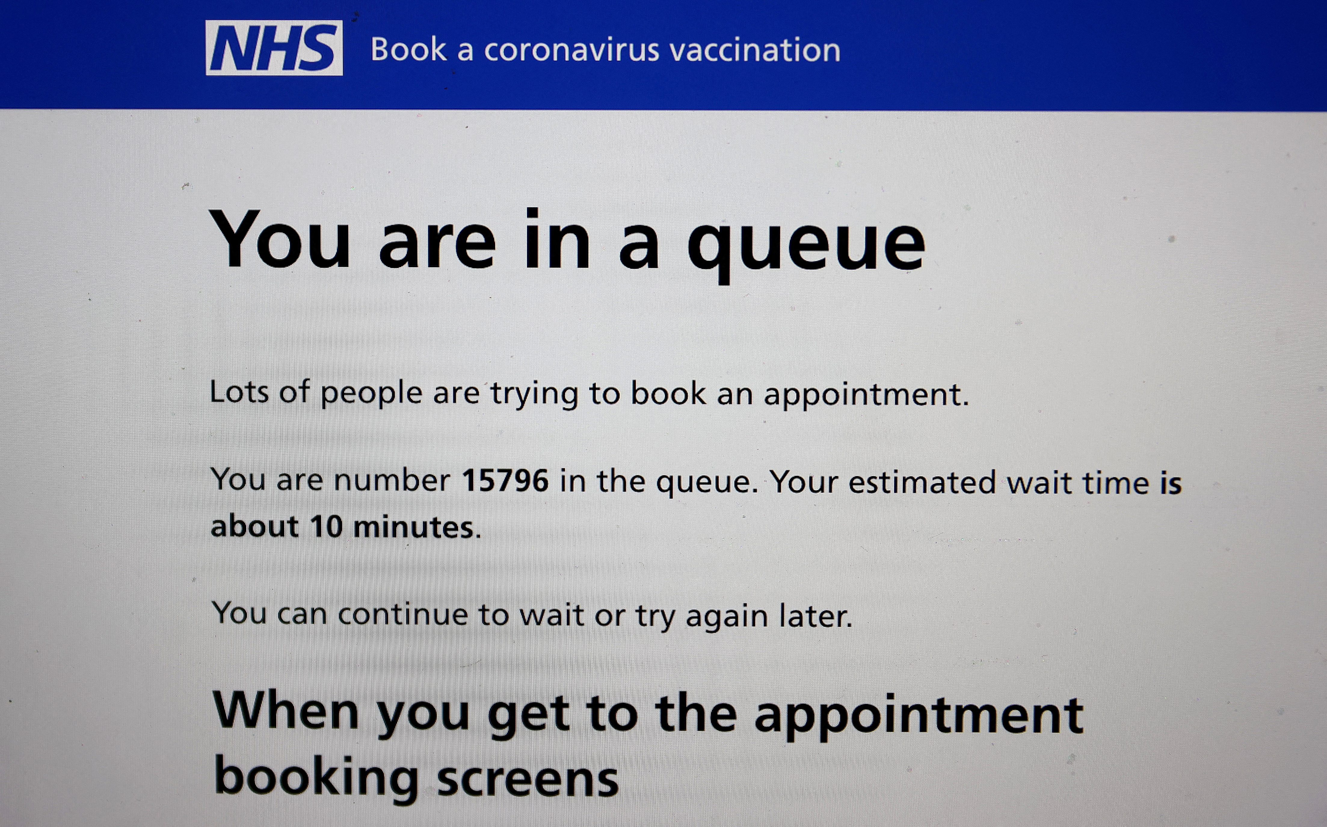 Photo illustration of a laptop screen showing information on NHS COVID-19 vaccination booking website