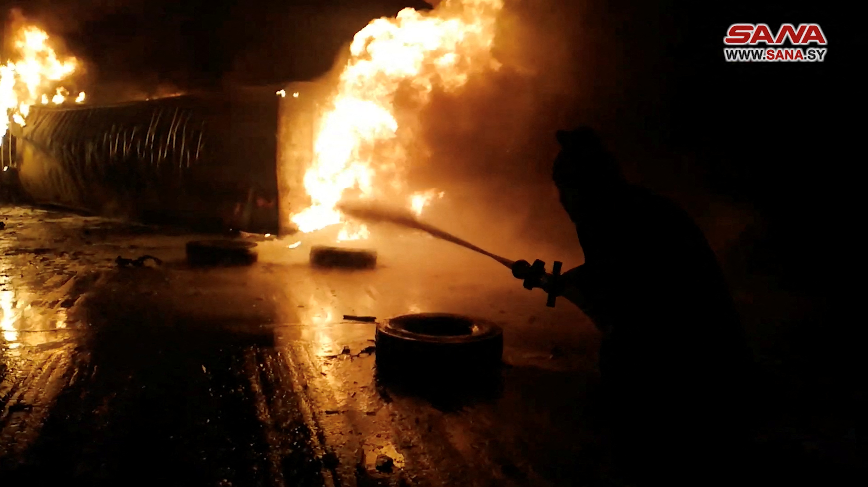 A still image from a video footage shows a firefighter dousing flames at the Syrian port of Latakia