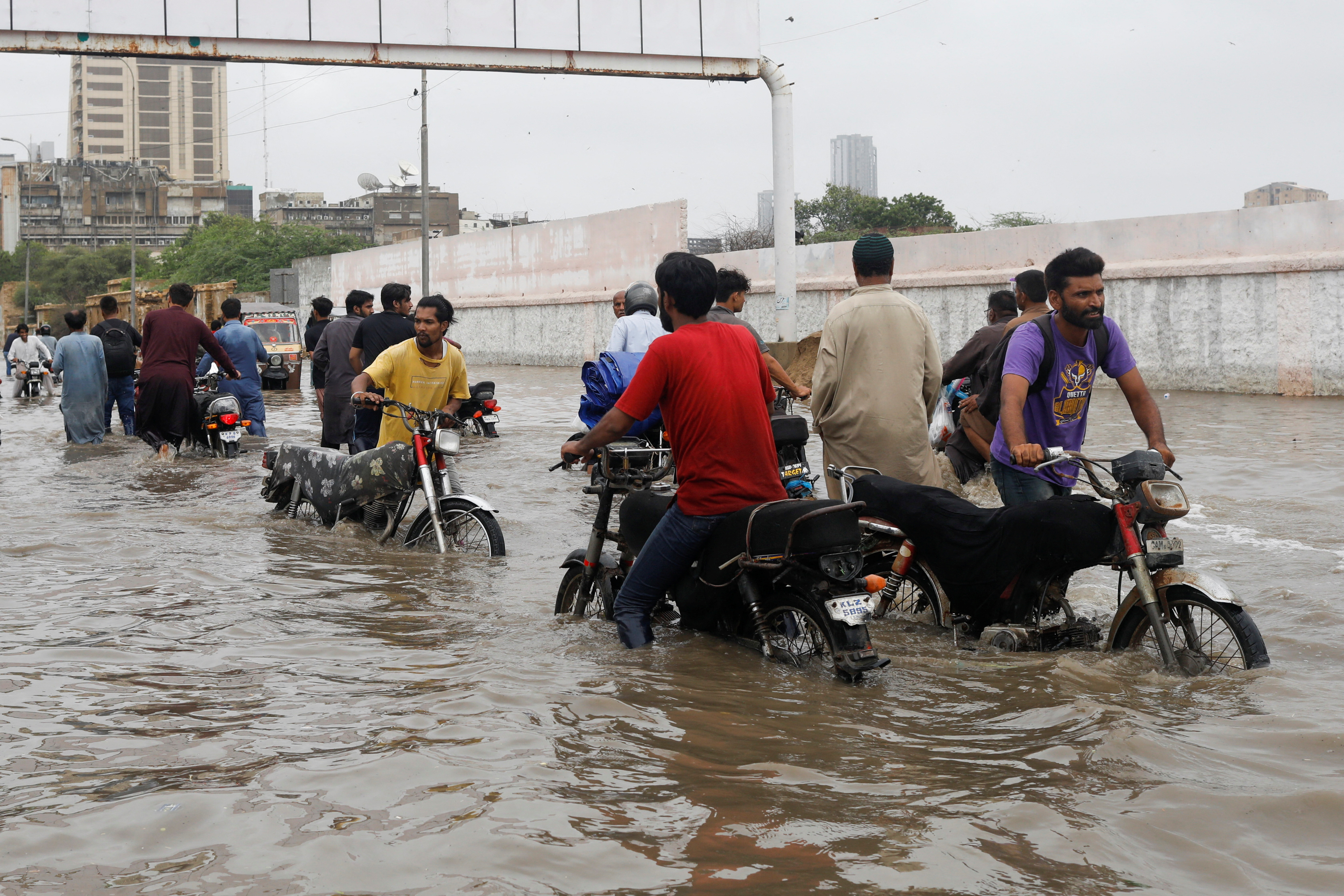 Residents commute through a flooded road during the monsoon season, in Karachi