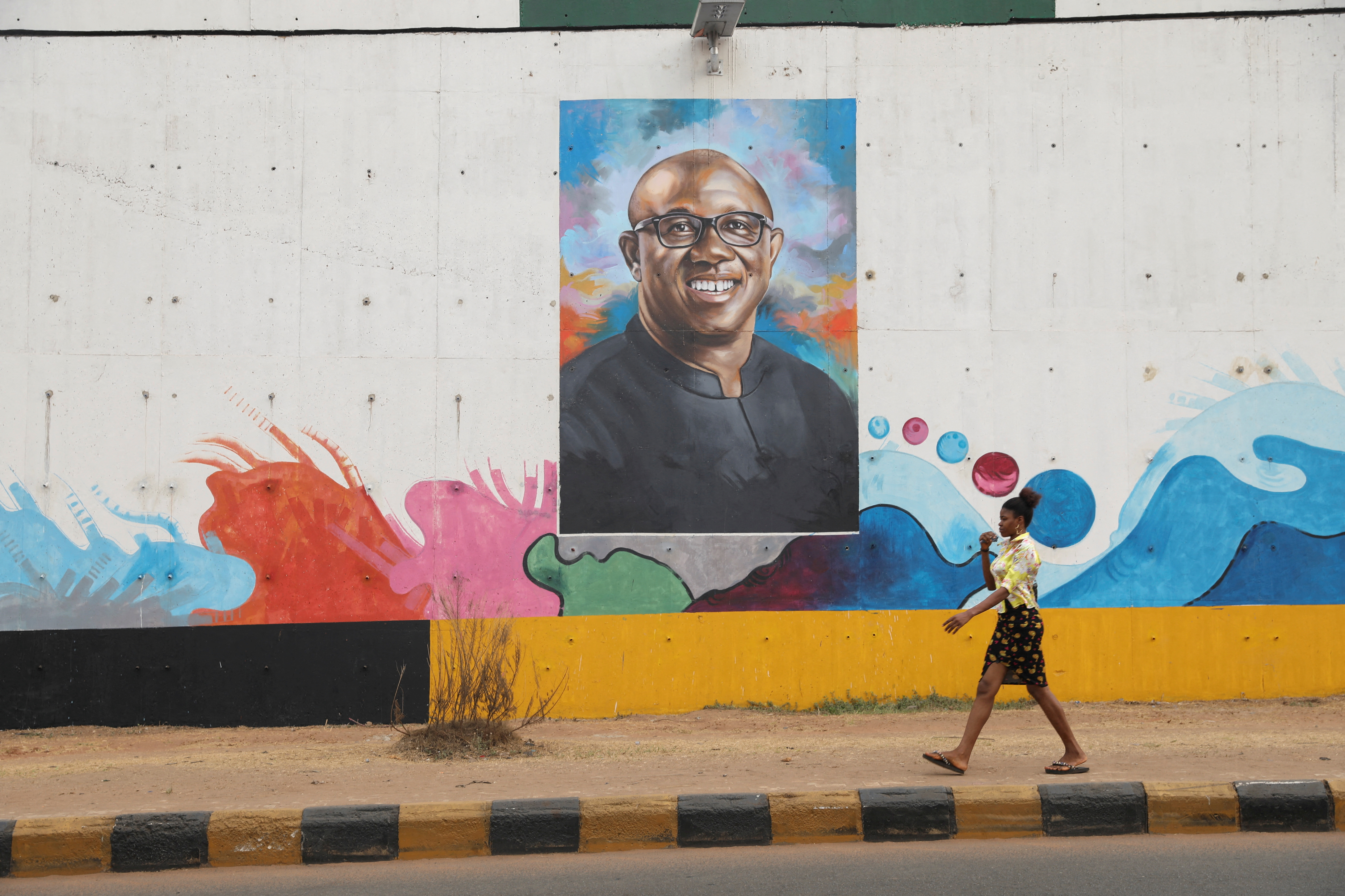 A woman walks past a graffiti depicting Labour Party (LP) Presidential candidate, Peter Obi, ahead of Nigeria's Presidential election in Awka