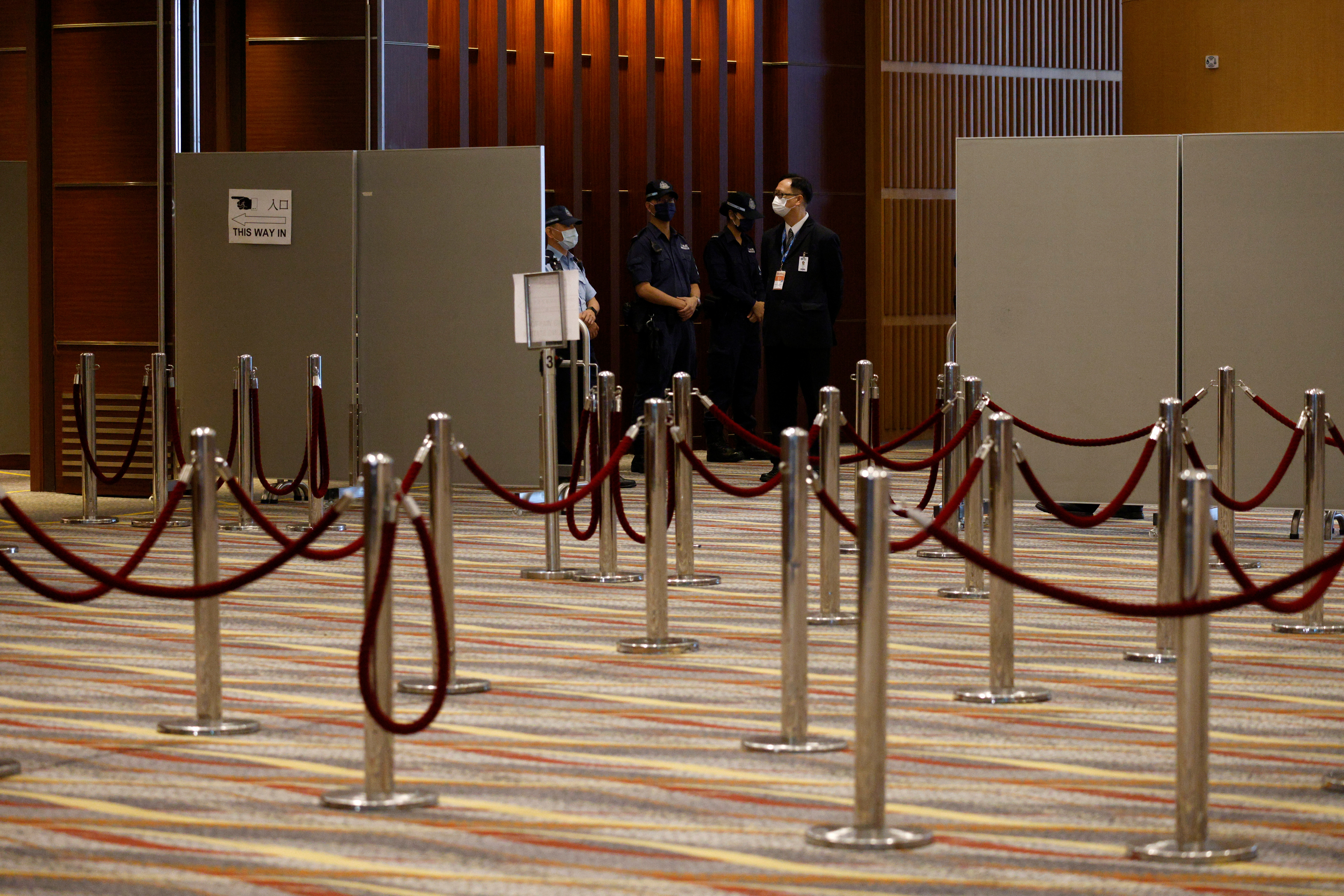 Police stand guard at a polling station during voting of the election committee, in Hong Kong