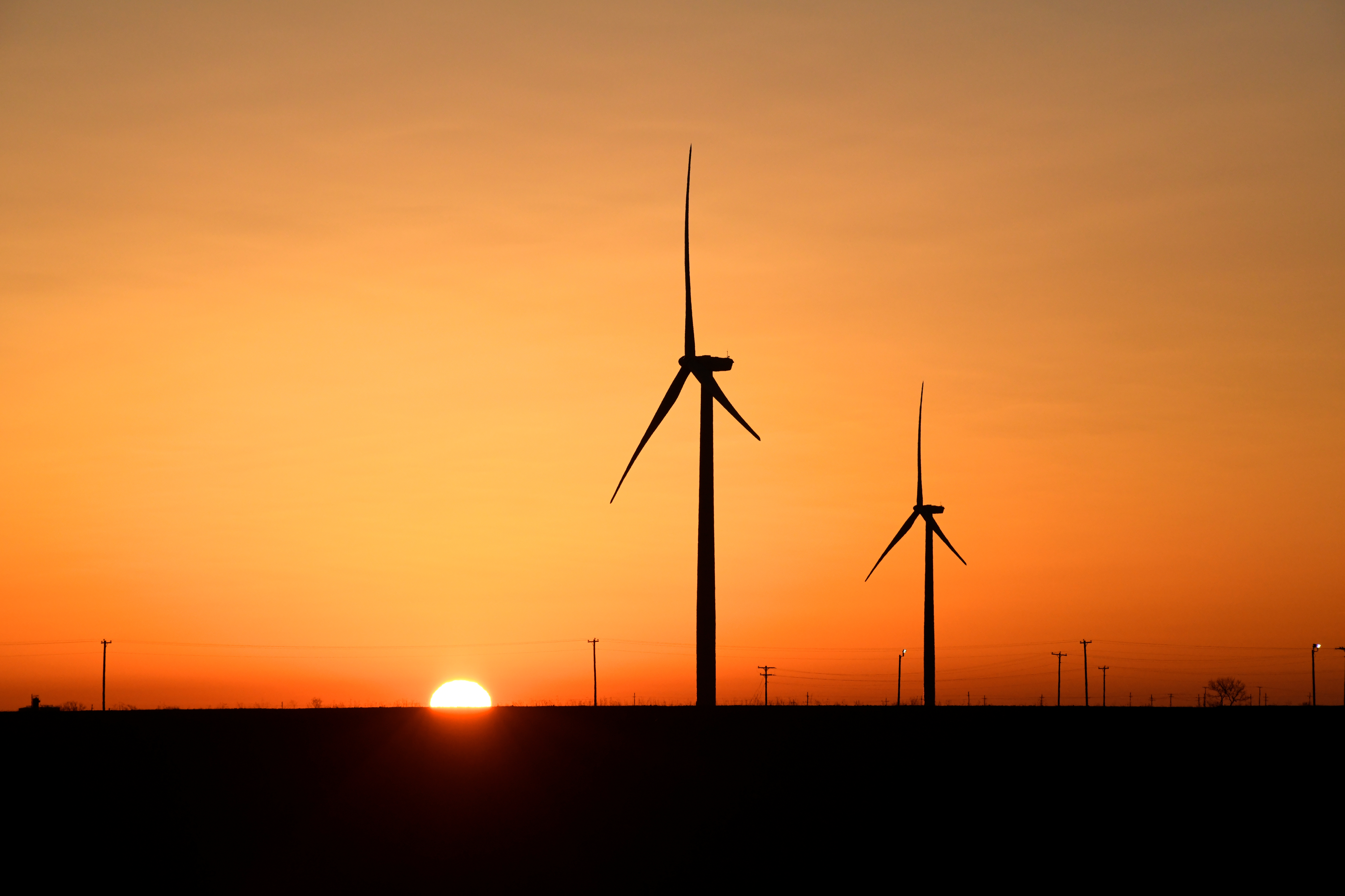 Wind turbines operate at sunrise in the Permian Basin oil and natural gas production area in Big Spring