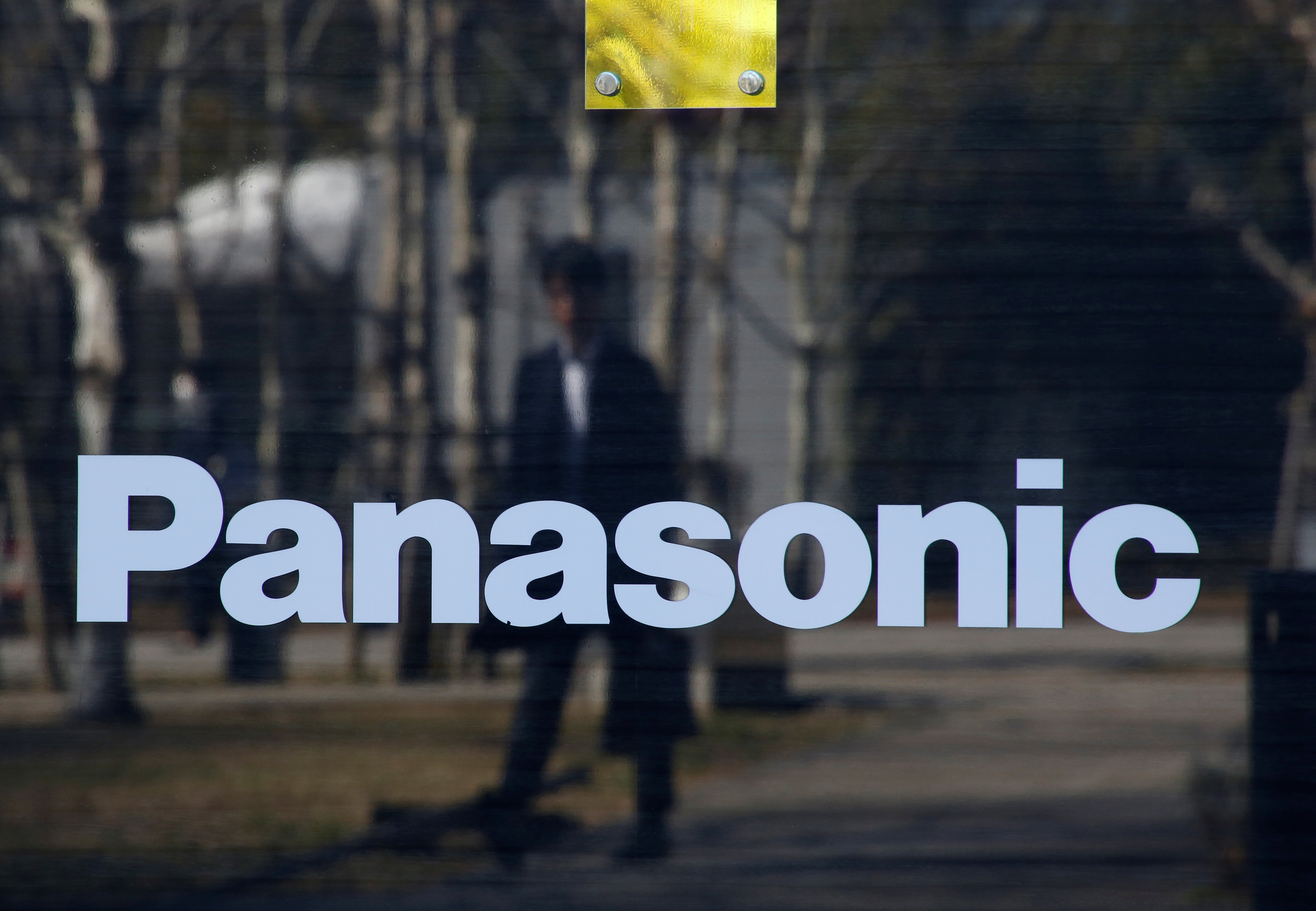 A man is reflected on Panasonic Corp's logo at Panasonic Center in Tokyo