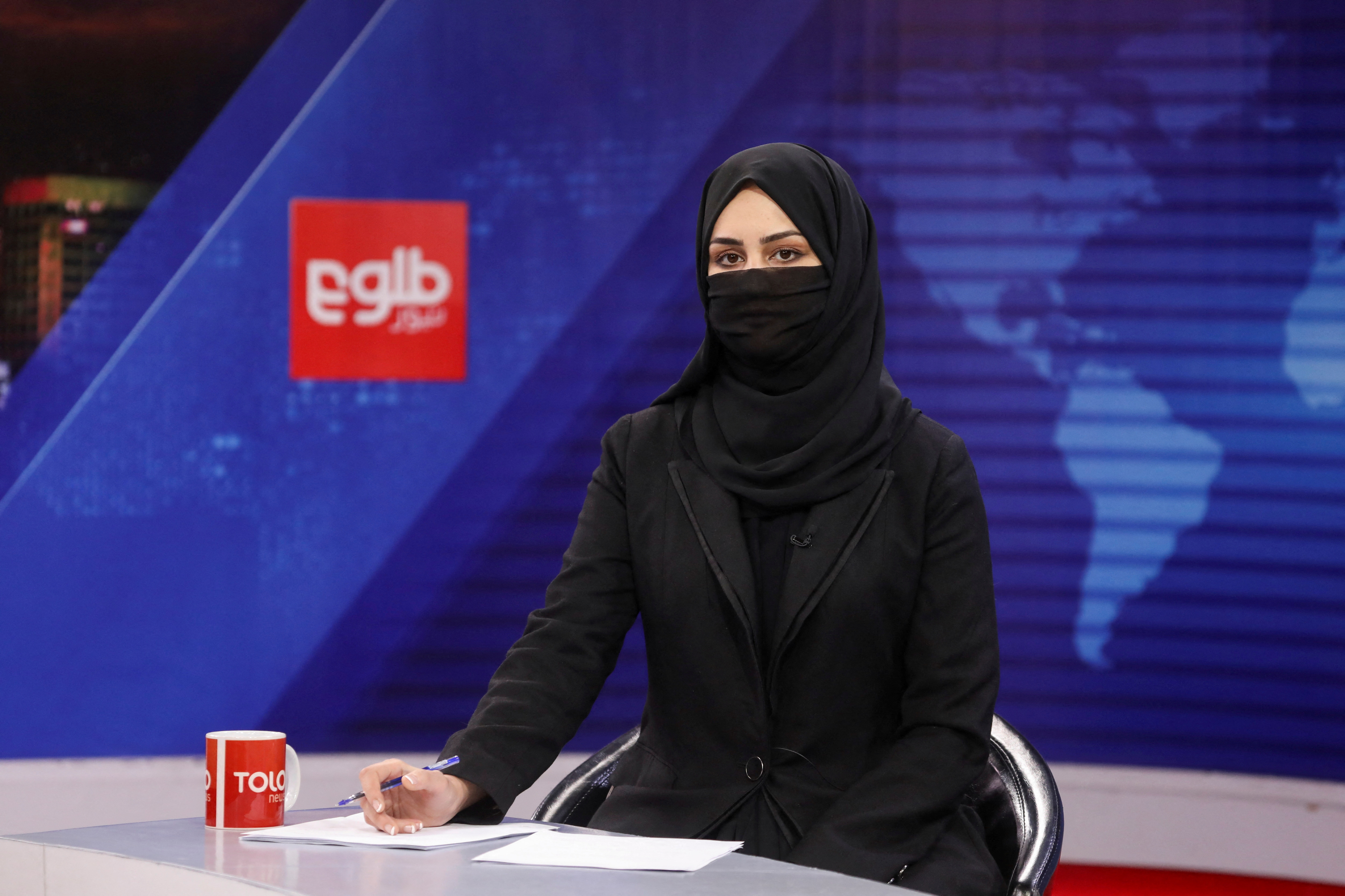 A female presenter for Tolo News, Khatereh Ahmadi, while covering her face, works in a newsroom at Tolo TV station in Kabul