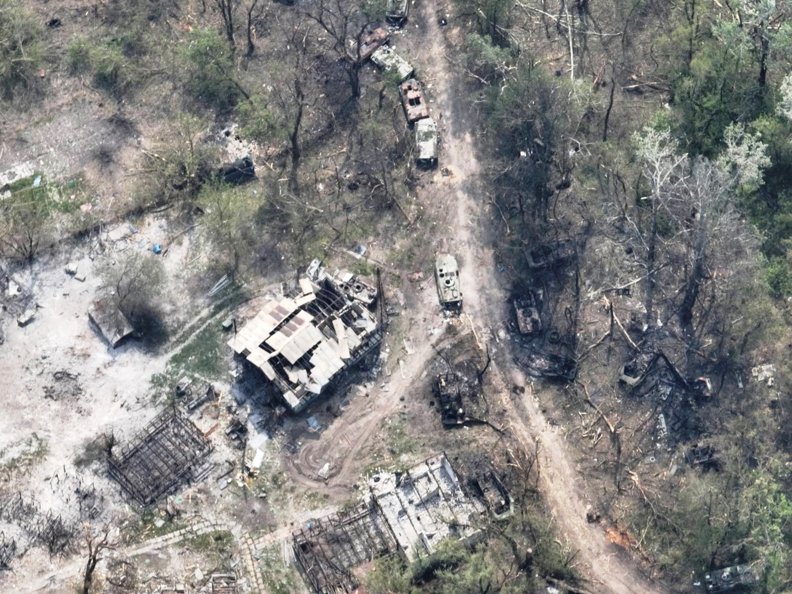 An aerial view of destroyed buildings and burnt vehicles on the banks of Siverskyi Donets River
