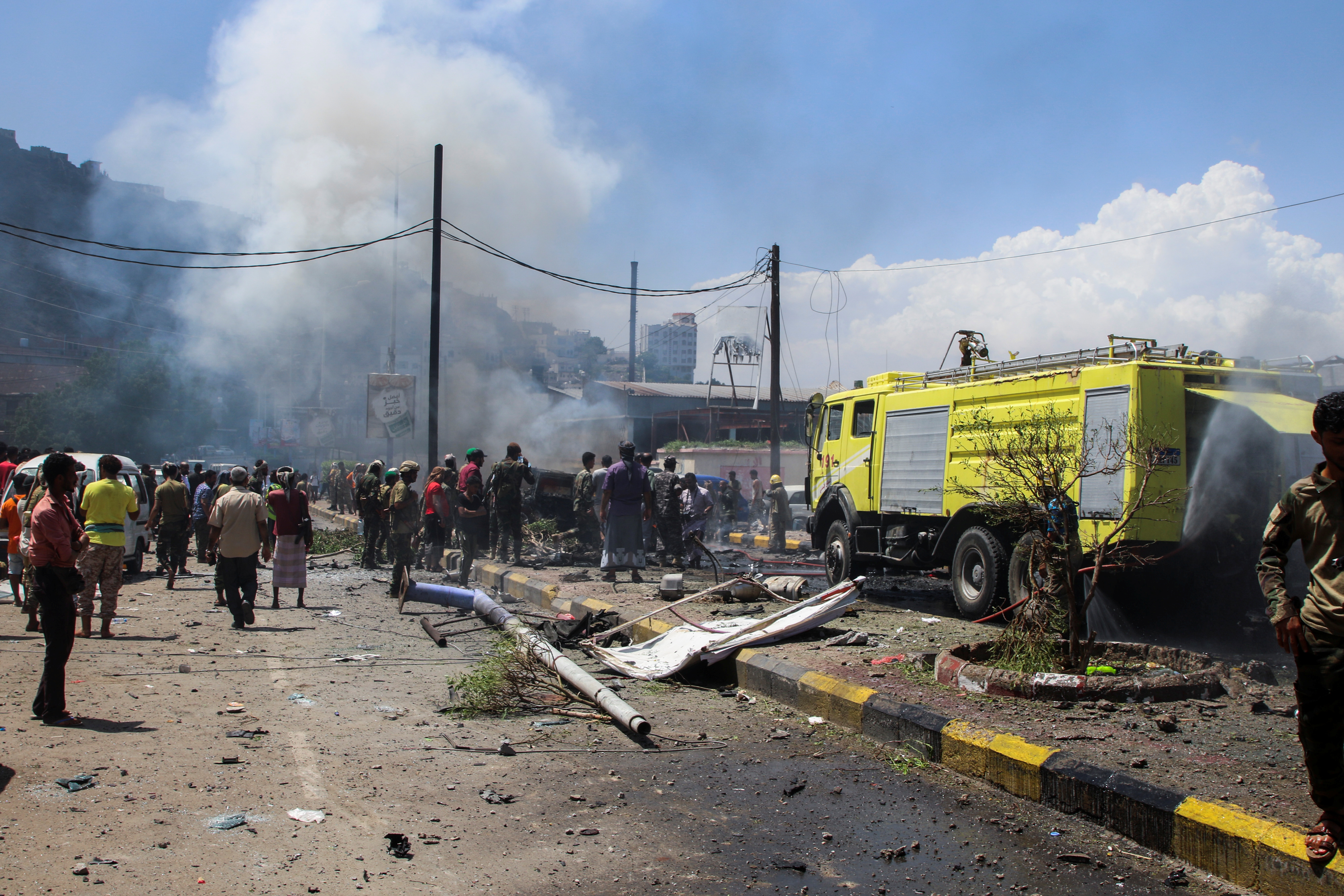 Policemen and firefighters work at the scene of a blast in Aden