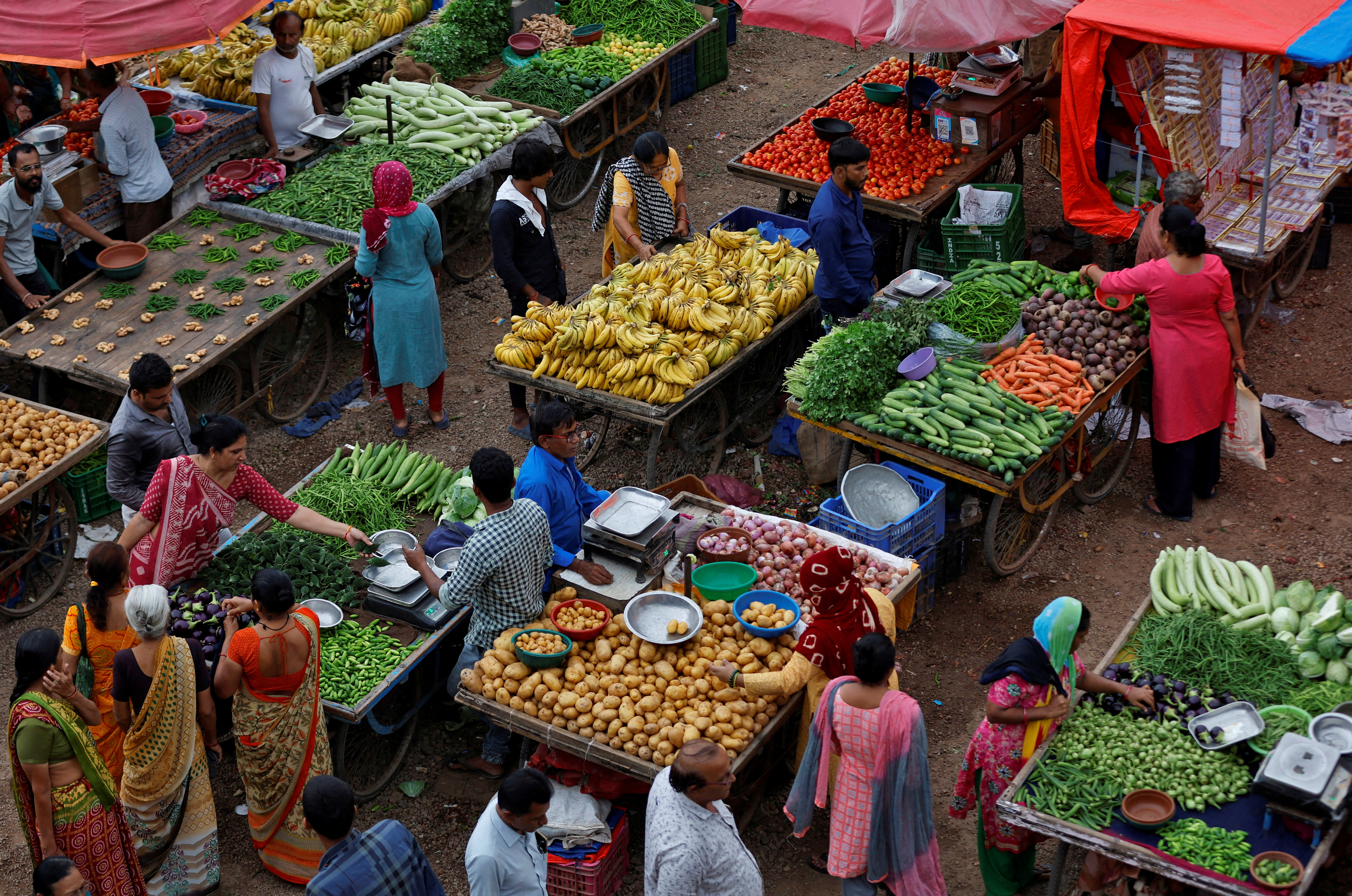 Customers buy fruits and vegetables at an open air evening market in Ahmedabad, India