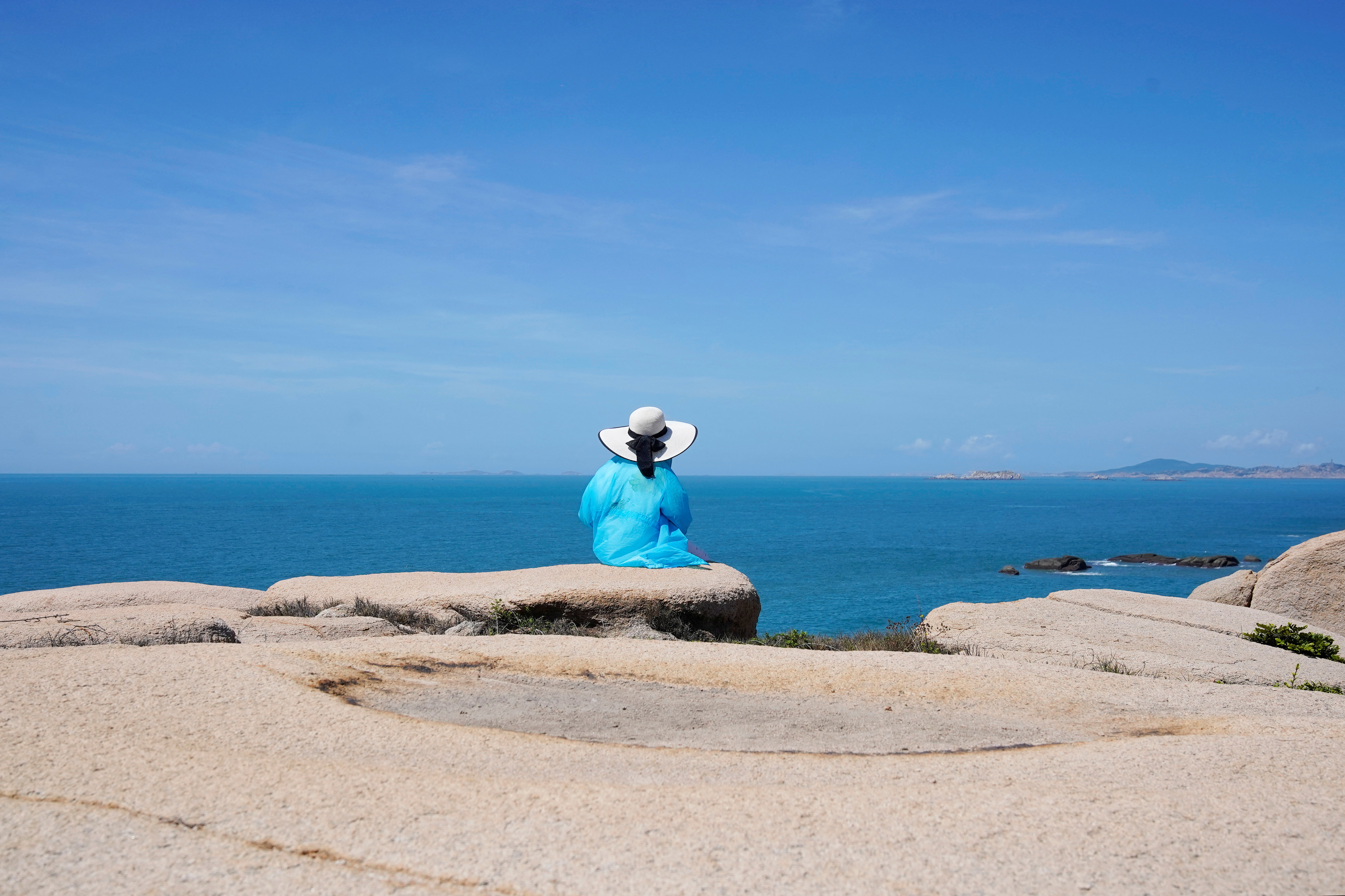 A tourist sits facing the Taiwan Strait in Pingtan island