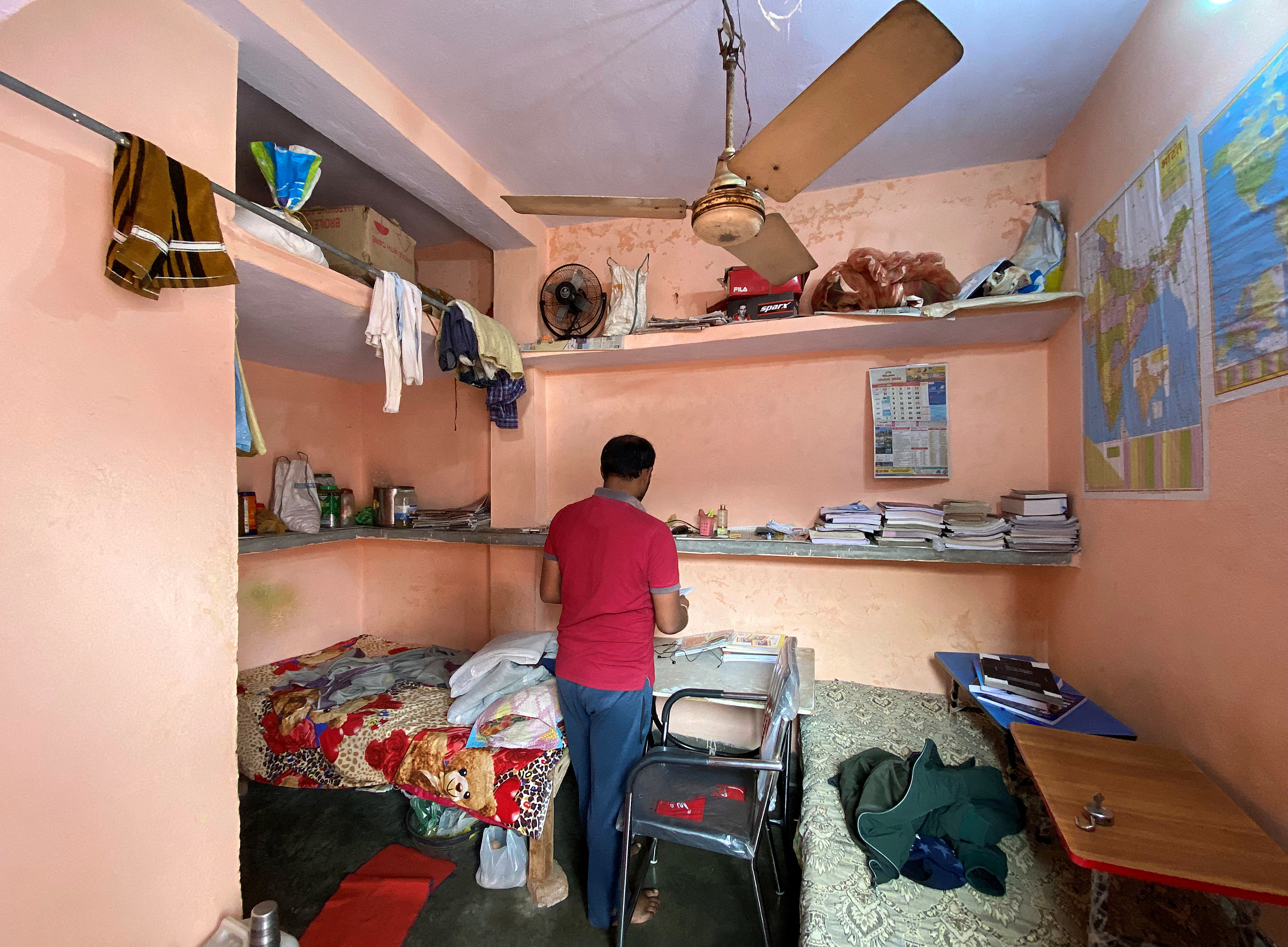 Niranjan Kumar checks out a notebook in his dormitory room in Patna