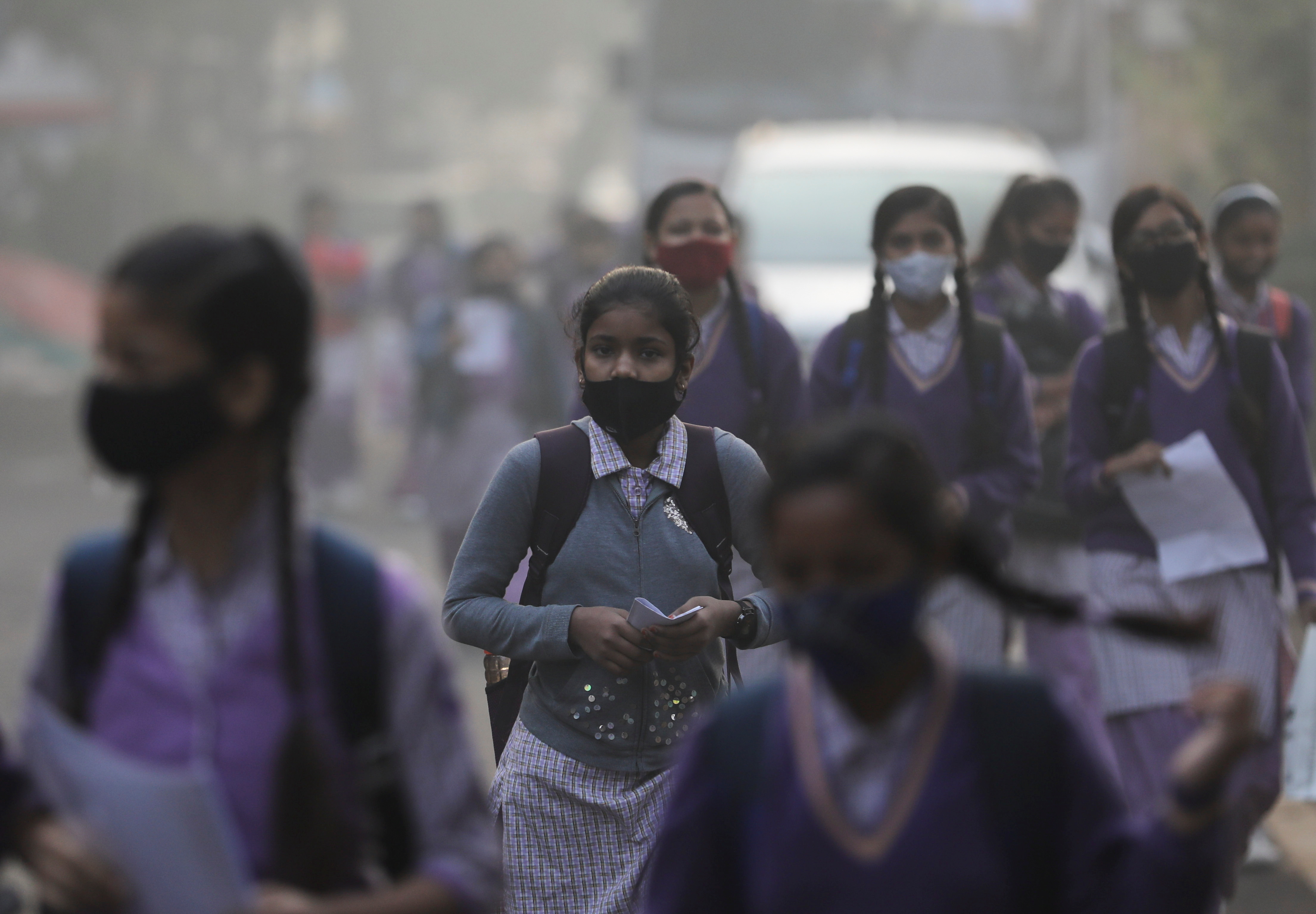 Le ragazze della scuola si dirigono verso la scuola che ha riaperto dopo essere stata chiusa per quasi 15 giorni a causa dell'aumento dell'inquinamento atmosferico, in una mattina piena di smog a Nuova Delhi