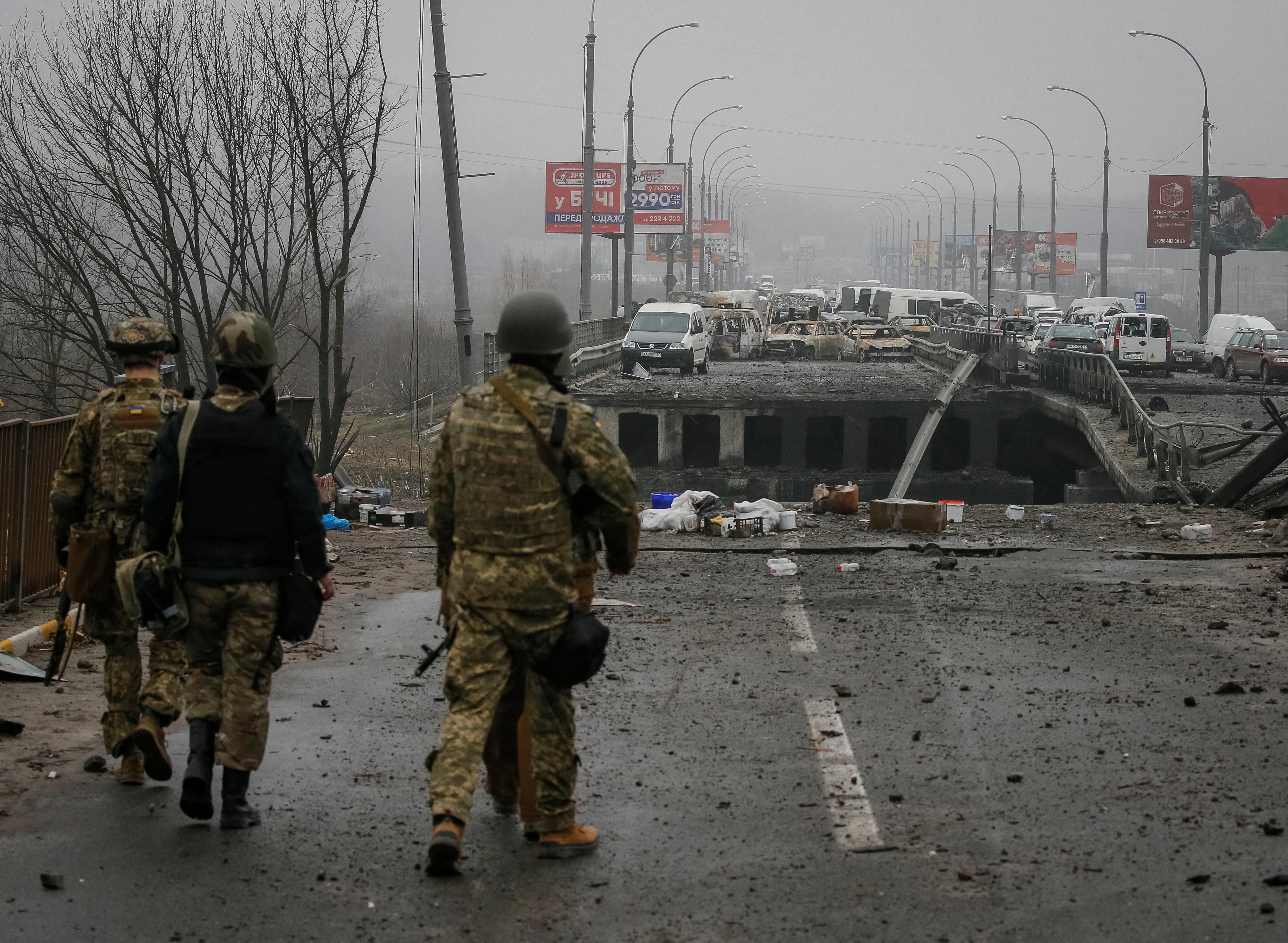 Ukrainian servicemen stand by a destroyed bridge as Russia's invasion of Ukraine continues, in the town of Irpin outside Kyiv